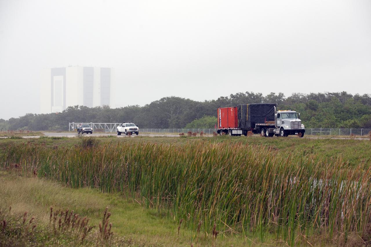 CAPE CANAVERAL, Fla. -- At NASA’s Kennedy Space Center in Florida, a flatbed truck carrying the Project Morpheus lander arrives at the Shuttle Landing Facility, or SLF. Testing of the prototype lander has been ongoing at NASA’s Johnson Space Center in Houston in preparation for free flight testing at Kennedy. The SLF will provide the lander with the kind of field necessary for realistic testing, complete with rocks, craters and hazards to avoid. Morpheus utilizes an autonomous landing and hazard avoidance technology, or ALHAT, payload that will allow it to navigate to clear landing sites amidst rocks, craters and other hazards during its descent. Project Morpheus is one of 20 small projects comprising the Advanced Exploration Systems, or AES, program in NASA’s Human Exploration and Operations Mission Directorate. AES projects pioneer new approaches for rapidly developing prototype systems, demonstrating key capabilities and validating operational concepts for future human missions beyond Earth orbit. For more information on Project Morpheus, visit http://www.nasa.gov/centers/johnson/exploration/morpheus/index.html. Photo credit: NASA/Kim Shiflett