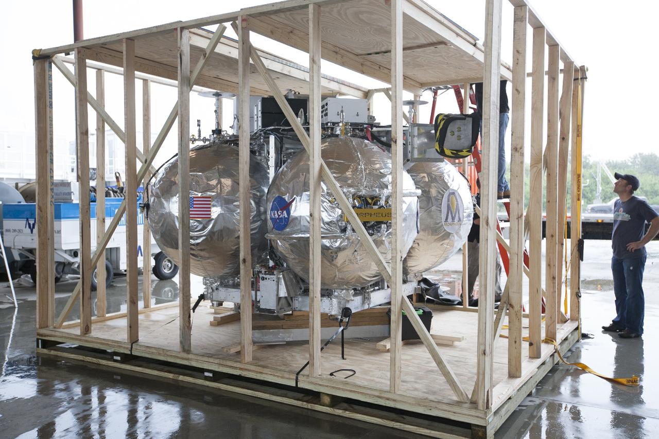 CAPE CANAVERAL, Fla. -- At NASA’s Kennedy Space Center in Florida, the Project Morpheus lander has been offloaded from a flatbed truck and sits inside a protective crate inside a support building at the Shuttle Landing Facility, or SLF. Testing of the prototype lander has been ongoing at NASA’s Johnson Space Center in Houston in preparation for free flight testing at Kennedy. The SLF will provide the lander with the kind of field necessary for realistic testing, complete with rocks, craters and hazards to avoid. Morpheus utilizes an autonomous landing and hazard avoidance technology, or ALHAT, payload that will allow it to navigate to clear landing sites amidst rocks, craters and other hazards during its descent. Project Morpheus is one of 20 small projects comprising the Advanced Exploration Systems, or AES, program in NASA’s Human Exploration and Operations Mission Directorate. AES projects pioneer new approaches for rapidly developing prototype systems, demonstrating key capabilities and validating operational concepts for future human missions beyond Earth orbit. For more information on Project Morpheus, visit http://www.nasa.gov/centers/johnson/exploration/morpheus/index.html. Photo credit: NASA/Kim Shiflett