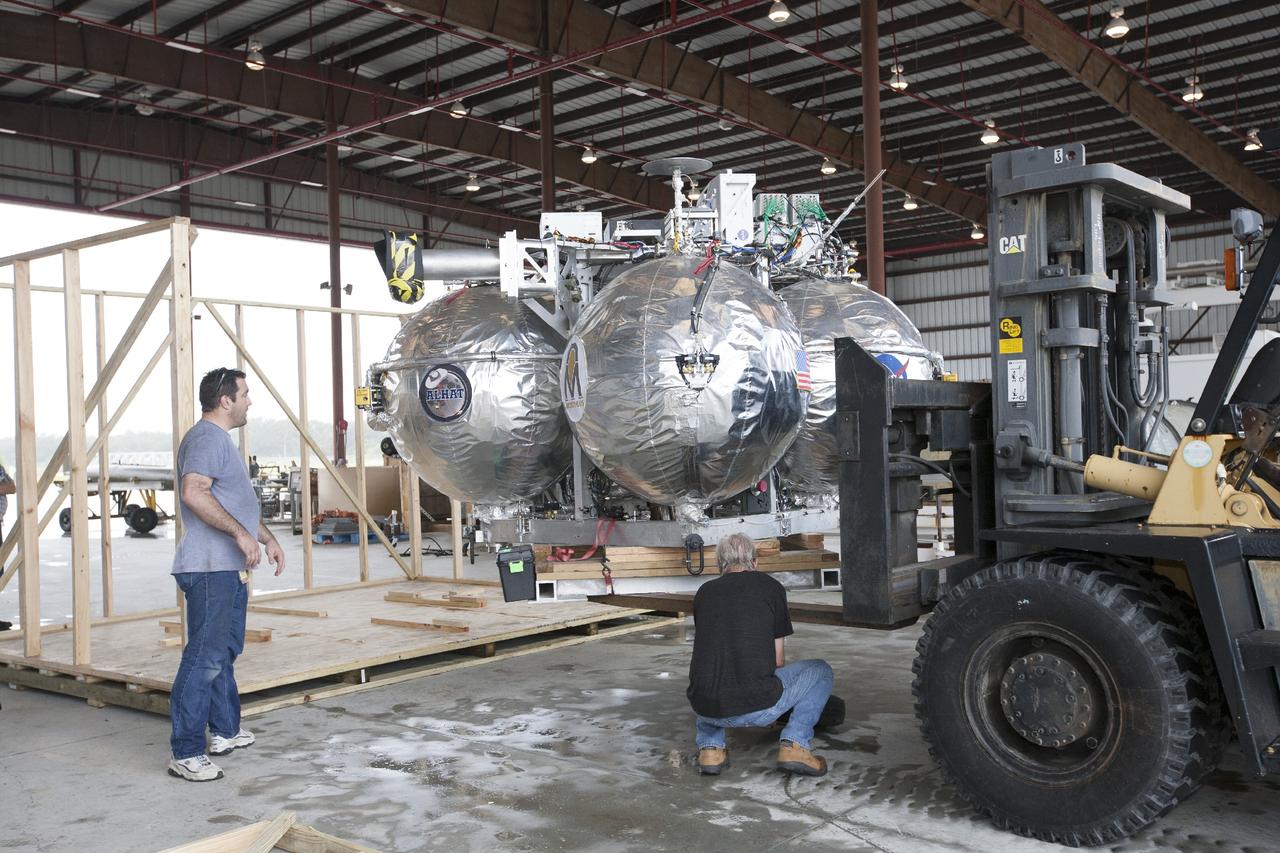 CAPE CANAVERAL, Fla. -- At NASA’s Kennedy Space Center in Florida, technicians remove the Project Morpheus lander from a protective crate inside a support building at the Shuttle Landing Facility, or SLF. Testing of the prototype lander has been ongoing at NASA’s Johnson Space Center in Houston in preparation for free flight testing at Kennedy. The SLF will provide the lander with the kind of field necessary for realistic testing, complete with rocks, craters and hazards to avoid. Morpheus utilizes an autonomous landing and hazard avoidance technology, or ALHAT, payload that will allow it to navigate to clear landing sites amidst rocks, craters and other hazards during its descent. Project Morpheus is one of 20 small projects comprising the Advanced Exploration Systems, or AES, program in NASA’s Human Exploration and Operations Mission Directorate. AES projects pioneer new approaches for rapidly developing prototype systems, demonstrating key capabilities and validating operational concepts for future human missions beyond Earth orbit. For more information on Project Morpheus, visit http://www.nasa.gov/centers/johnson/exploration/morpheus/index.html. Photo credit: NASA/Kim Shiflett