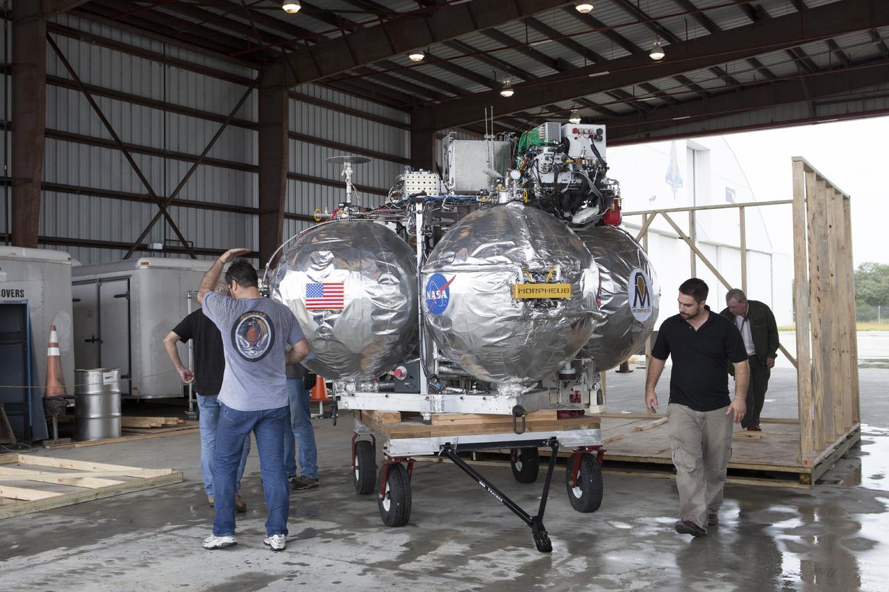 CAPE CANAVERAL, Fla. -- At NASA’s Kennedy Space Center in Florida, technicians position the Project Morpheus lander onto a transporter inside a support building at the Shuttle Landing Facility, or SLF. Testing of the prototype lander has been ongoing at NASA’s Johnson Space Center in Houston in preparation for free flight testing at Kennedy. The SLF will provide the lander with the kind of field necessary for realistic testing, complete with rocks, craters and hazards to avoid. Morpheus utilizes an autonomous landing and hazard avoidance technology, or ALHAT, payload that will allow it to navigate to clear landing sites amidst rocks, craters and other hazards during its descent. Project Morpheus is one of 20 small projects comprising the Advanced Exploration Systems, or AES, program in NASA’s Human Exploration and Operations Mission Directorate. AES projects pioneer new approaches for rapidly developing prototype systems, demonstrating key capabilities and validating operational concepts for future human missions beyond Earth orbit. For more information on Project Morpheus, visit http://www.nasa.gov/centers/johnson/exploration/morpheus/index.html. Photo credit: NASA/Kim Shiflett