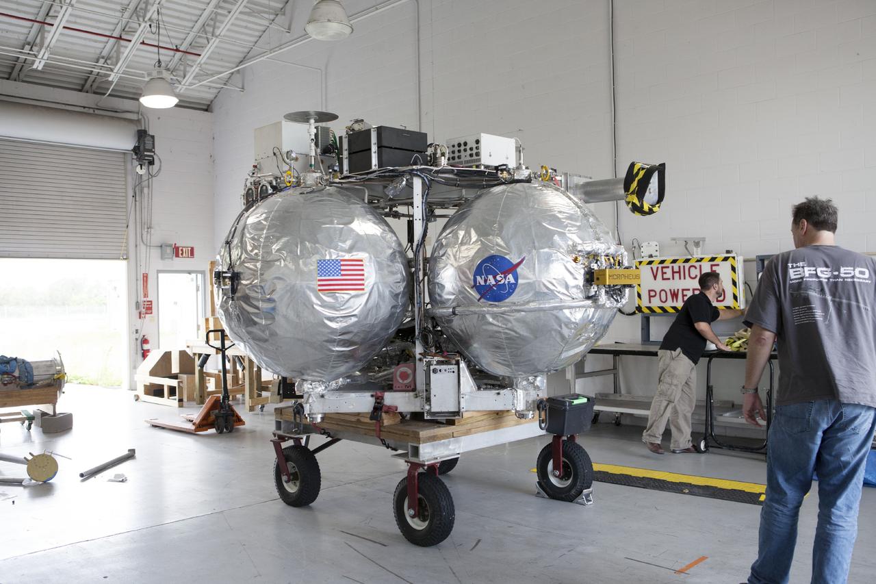 CAPE CANAVERAL, Fla. -- At NASA’s Kennedy Space Center in Florida, the Project Morpheus lander is moved into the bay of a support building at the Shuttle Landing Facility, or SLF. Testing of the prototype lander has been ongoing at NASA’s Johnson Space Center in Houston in preparation for free flight testing at Kennedy. The SLF will provide the lander with the kind of field necessary for realistic testing, complete with rocks, craters and hazards to avoid. Morpheus utilizes an autonomous landing and hazard avoidance technology, or ALHAT, payload that will allow it to navigate to clear landing sites amidst rocks, craters and other hazards during its descent. Project Morpheus is one of 20 small projects comprising the Advanced Exploration Systems, or AES, program in NASA’s Human Exploration and Operations Mission Directorate. AES projects pioneer new approaches for rapidly developing prototype systems, demonstrating key capabilities and validating operational concepts for future human missions beyond Earth orbit. For more information on Project Morpheus, visit http://www.nasa.gov/centers/johnson/exploration/morpheus/index.html. Photo credit: NASA/Kim Shiflett