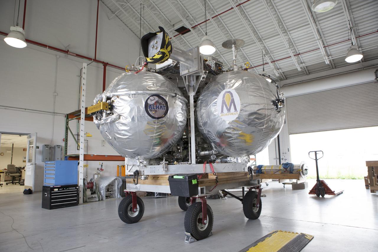 CAPE CANAVERAL, Fla. -- At NASA’s Kennedy Space Center in Florida, the Project Morpheus lander sits inside the bay of a support building at the Shuttle Landing Facility, or SLF. Testing of the prototype lander has been ongoing at NASA’s Johnson Space Center in Houston in preparation for free flight testing at Kennedy. The SLF will provide the lander with the kind of field necessary for realistic testing, complete with rocks, craters and hazards to avoid. Morpheus utilizes an autonomous landing and hazard avoidance technology, or ALHAT, payload that will allow it to navigate to clear landing sites amidst rocks, craters and other hazards during its descent. Project Morpheus is one of 20 small projects comprising the Advanced Exploration Systems, or AES, program in NASA’s Human Exploration and Operations Mission Directorate. AES projects pioneer new approaches for rapidly developing prototype systems, demonstrating key capabilities and validating operational concepts for future human missions beyond Earth orbit. For more information on Project Morpheus, visit http://www.nasa.gov/centers/johnson/exploration/morpheus/index.html. Photo credit: NASA/Kim Shiflett