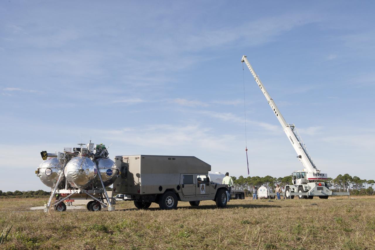 CAPE CANAVERAL, Fla. – The Project Morpheus prototype lander is positioned at the midfield of the Shuttle Landing Facility at NASA’s Kennedy Space Center in Florida to prepare it for a dress rehearsal of a tethered flight test. The lander will be transported to a launch platform at the north end of the landing facility. Testing of the prototype lander was performed at NASA’s Johnson Space Center in Houston in preparation for tethered and free flight testing at Kennedy. The landing facility will provide the lander with the kind of field necessary for realistic testing, complete with rocks, craters and hazards to avoid. Morpheus utilizes an autonomous landing and hazard avoidance technology, or ALHAT, payload that will allow it to navigate to clear landing sites amidst rocks, craters and other hazards during its descent. Project Morpheus is being managed under the Advanced Exploration Systems, or AES, Division in NASA’s Human Exploration and Operations Mission Directorate. The efforts in AES pioneer new approaches for rapidly developing prototype systems, demonstrating key capabilities and validating operational concepts for future human missions beyond Earth orbit. For more information on Project Morpheus, visit http://morpheuslander.jsc.nasa.gov. Photo credit: NASA/Kim Shiflett
