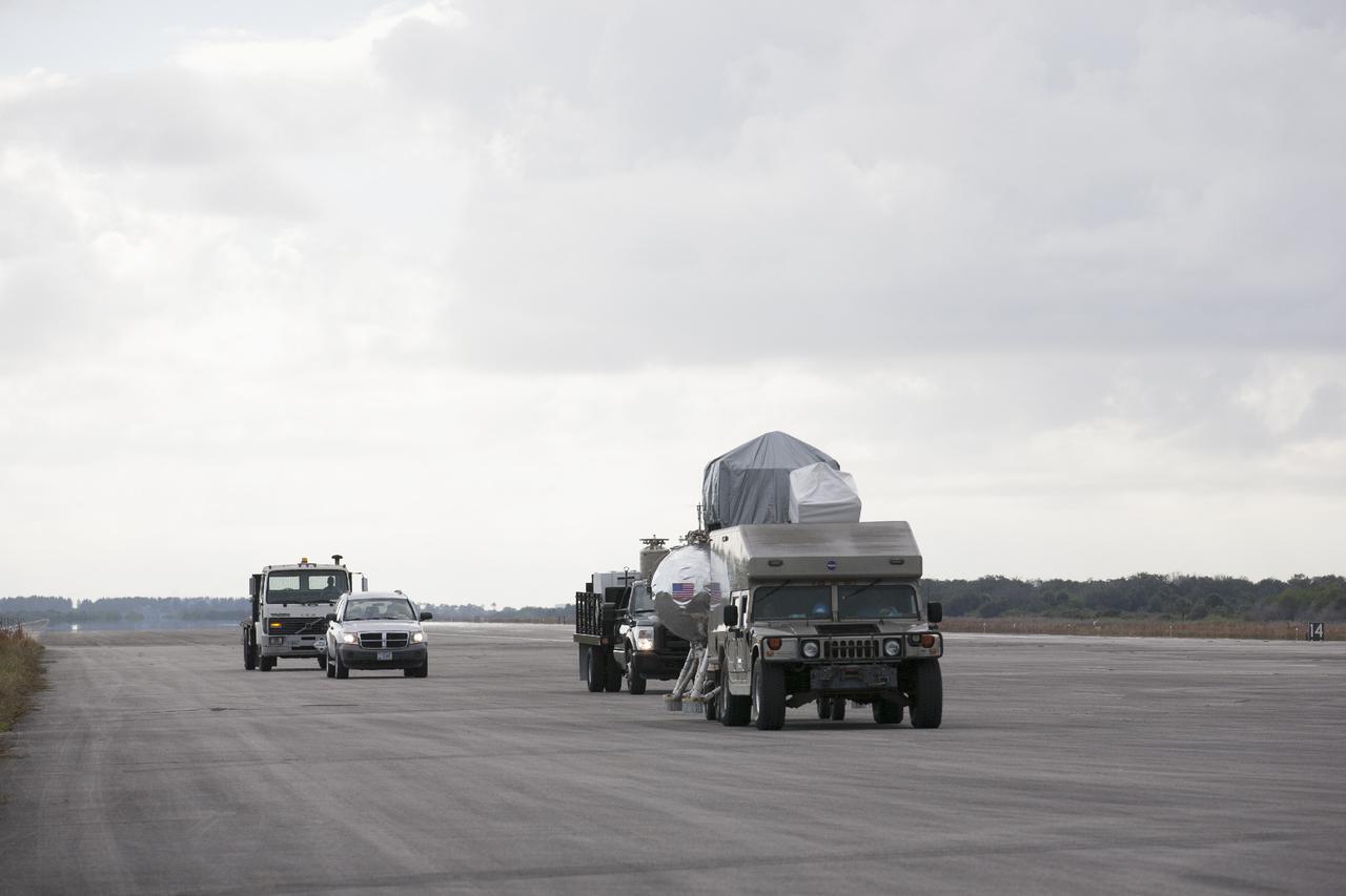 CAPE CANAVERAL, Fla. – At NASA’s Kennedy Space Center in Florida, a convoy of vehicles accompanies the Project Morpheus prototype lander to a transportable launch platform positioned at the north end of the Shuttle Landing Facility. The lander will be prepared for a tethered test that includes lifting it 20 feet by crane, ascending another 10 feet, maneuvering backwards 10 feet, and then flying forward and descending to its original position, landing at the end of the tether. Testing of the prototype lander was performed at NASA’s Johnson Space Center in Houston in preparation for tethered and free flight testing at Kennedy. The landing facility will provide the lander with the kind of field necessary for realistic testing, complete with rocks, craters and hazards to avoid. Morpheus utilizes an autonomous landing and hazard avoidance technology, or ALHAT, payload that will allow it to navigate to clear landing sites amidst rocks, craters and other hazards during its descent. Project Morpheus is being managed under the Advanced Exploration Systems, or AES, Division in NASA’s Human Exploration and Operations Mission Directorate. The efforts in AES pioneer new approaches for rapidly developing prototype systems, demonstrating key capabilities and validating operational concepts for future human missions beyond Earth orbit. For more information on Project Morpheus, visit http://morpheuslander.jsc.nasa.gov. Photo credit: NASA/Kim Shiflett
