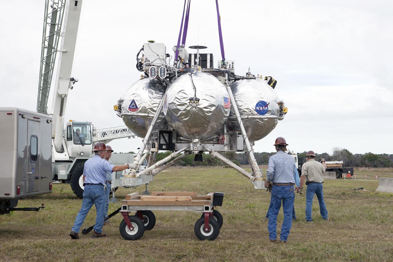 CAPE CANAVERAL, Fla. – At NASA’s Kennedy Space Center in Florida, the Project Morpheus prototype lander has been attached to a tether and is being prepared for placement on a transportable launch platform positioned at the north end of the Shuttle Landing Facility. The lander will be prepared for a tethered test that includes lifting it 20 feet by crane, ascending another 10 feet, maneuvering backwards 10 feet, and then flying forward and descending to its original position, landing at the end of the tether. Testing of the prototype lander was performed at NASA’s Johnson Space Center in Houston in preparation for tethered and free flight testing at Kennedy. The landing facility will provide the lander with the kind of field necessary for realistic testing, complete with rocks, craters and hazards to avoid. Morpheus utilizes an autonomous landing and hazard avoidance technology, or ALHAT, payload that will allow it to navigate to clear landing sites amidst rocks, craters and other hazards during its descent. Project Morpheus is being managed under the Advanced Exploration Systems, or AES, Division in NASA’s Human Exploration and Operations Mission Directorate. The efforts in AES pioneer new approaches for rapidly developing prototype systems, demonstrating key capabilities and validating operational concepts for future human missions beyond Earth orbit. For more information on Project Morpheus, visit http://morpheuslander.jsc.nasa.gov. Photo credit: NASA/Kim Shiflett