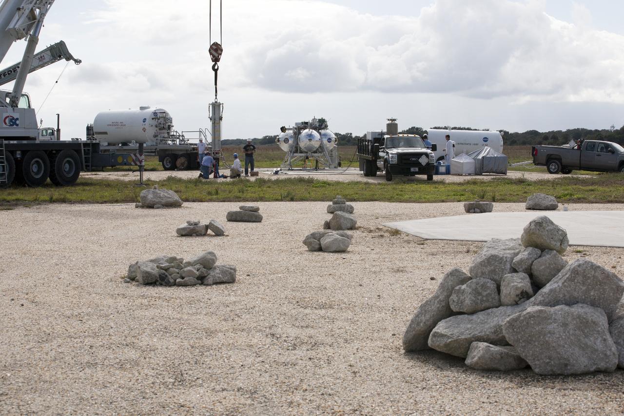CAPE CANAVERAL, Fla. – At NASA’s Kennedy Space Center in Florida, the Project Morpheus prototype lander has been positioned on a transportable launch platform at the north end of the Shuttle Landing Facility. A portion of the hazard field is in the foreground. The lander will be prepared for a tethered test that includes lifting it 20 feet by crane, ascending another 10 feet, maneuvering backwards 10 feet, and then flying forward and descending to its original position, landing at the end of the tether. Testing of the prototype lander was performed at NASA’s Johnson Space Center in Houston in preparation for tethered and free flight testing at Kennedy. The landing facility will provide the lander with the kind of field necessary for realistic testing, complete with rocks, craters and hazards to avoid. Morpheus utilizes an autonomous landing and hazard avoidance technology, or ALHAT, payload that will allow it to navigate to clear landing sites amidst rocks, craters and other hazards during its descent. Project Morpheus is being managed under the Advanced Exploration Systems, or AES, Division in NASA’s Human Exploration and Operations Mission Directorate. The efforts in AES pioneer new approaches for rapidly developing prototype systems, demonstrating key capabilities and validating operational concepts for future human missions beyond Earth orbit. For more information on Project Morpheus, visit http://morpheuslander.jsc.nasa.gov. Photo credit: NASA/Kim Shiflett