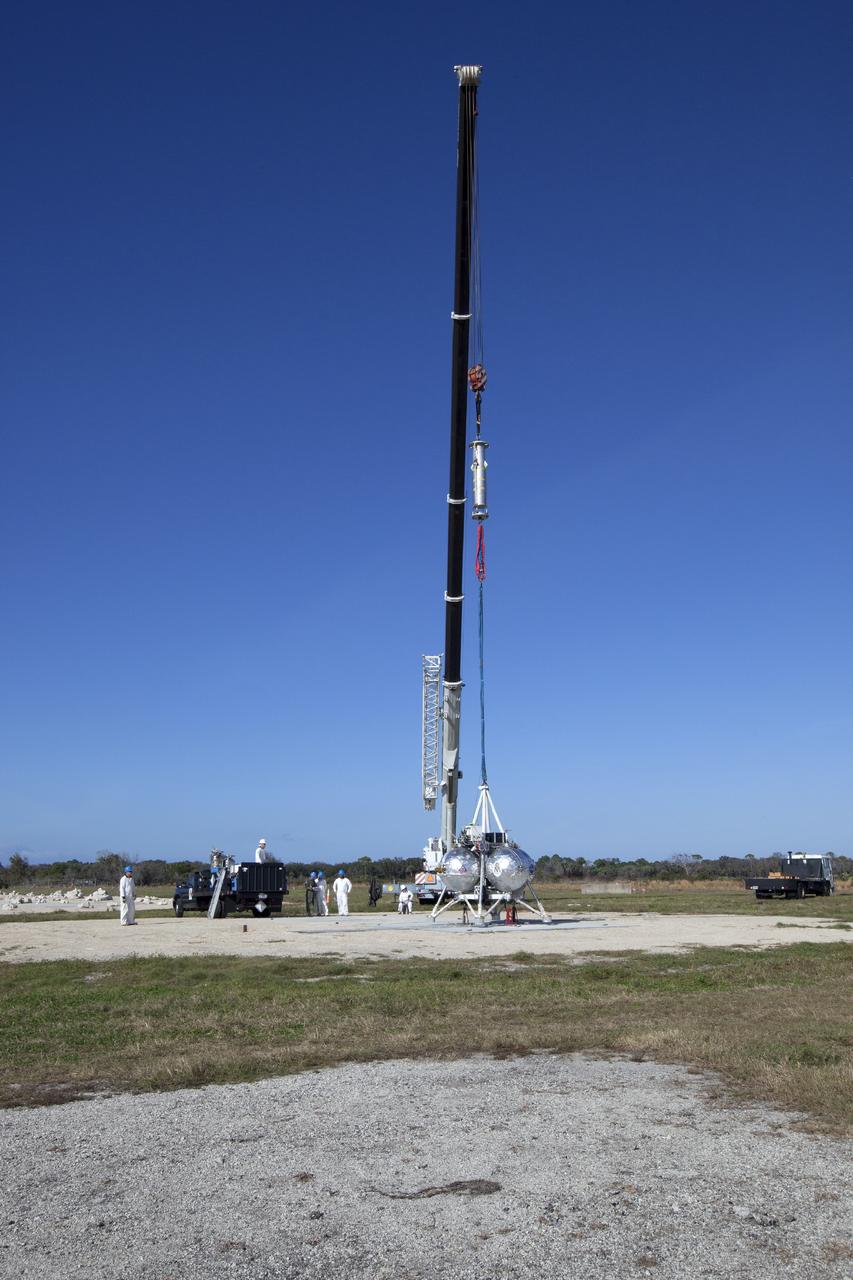 CAPE CANAVERAL, Fla. – At NASA’s Kennedy Space Center in Florida, the Project Morpheus prototype lander has been attached to a tether and is being prepared for a tether test on a transportable launch platform positioned at the north end of the Shuttle Landing Facility. The tether test includes lifting the lander 20 feet by crane, ascending another 10 feet, maneuvering backwards 10 feet, and then flying forward and descending to its original position, landing at the end of the tether. Testing of the prototype lander was performed at NASA’s Johnson Space Center in Houston in preparation for tethered and free flight testing at Kennedy. The landing facility will provide the lander with the kind of field necessary for realistic testing, complete with rocks, craters and hazards to avoid. Morpheus utilizes an autonomous landing and hazard avoidance technology, or ALHAT, payload that will allow it to navigate to clear landing sites amidst rocks, craters and other hazards during its descent. Project Morpheus is being managed under the Advanced Exploration Systems, or AES, Division in NASA’s Human Exploration and Operations Mission Directorate. The efforts in AES pioneer new approaches for rapidly developing prototype systems, demonstrating key capabilities and validating operational concepts for future human missions beyond Earth orbit. For more information on Project Morpheus, visit http://morpheuslander.jsc.nasa.gov. Photo credit: NASA/Daniel Casper