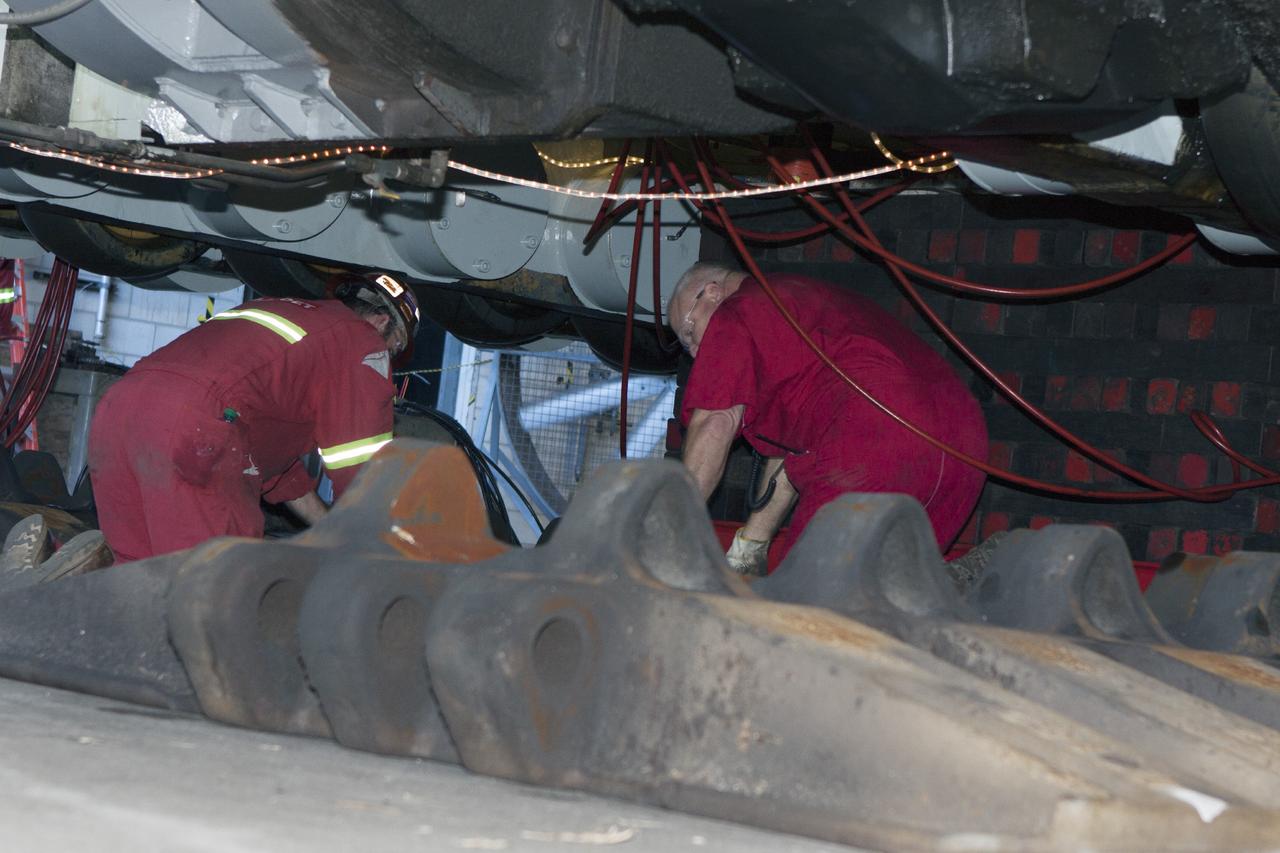 CAPE CANAVERAL, Fla. – Inside the Vehicle Assembly Building at NASA’s Kennedy Space Center in Florida, two ground support technicians check on crawler-transporter 2, or CT-2, so that work can begin to re-install the large crawler tracks. The crawler is being prepared for rollout in January 2014 to test the new bearings that were recently installed.    Work continues in high bay 2 to upgrade CT-2. The modifications are designed to ensure CT-2’s ability to transport launch vehicles currently in development, such as the agency’s Space Launch System, to the launch pad. The Ground Systems Development and Operations Program office at Kennedy is overseeing the upgrades. For more than 45 years the crawler-transporters were used to transport the mobile launcher platform and the Apollo-Saturn V rockets and, later, space shuttles to Launch Pads 39A and B. For more information, visit: http://www.nasa.gov/centers/kennedy/pdf/638823main_crawler-transporter.pdf. Photo credit: NASA/Jim Grossmann