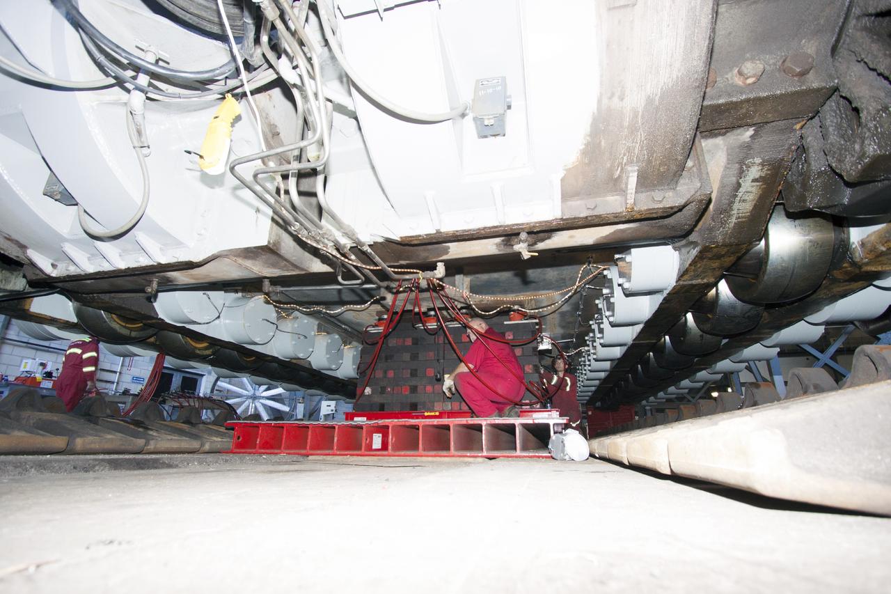 CAPE CANAVERAL, Fla. – Inside the Vehicle Assembly Building at NASA’s Kennedy Space Center in Florida, ground support technicians make some adjustment beneath the crawler so that work can begin to re-install the large crawler tracks. The crawler is being prepared for rollout in January 2014 to test the new bearings that were recently installed.    Work continues in high bay 2 to upgrade CT-2. The modifications are designed to ensure CT-2’s ability to transport launch vehicles currently in development, such as the agency’s Space Launch System, to the launch pad. The Ground Systems Development and Operations Program office at Kennedy is overseeing the upgrades. For more than 45 years the crawler-transporters were used to transport the mobile launcher platform and the Apollo-Saturn V rockets and, later, space shuttles to Launch Pads 39A and B. For more information, visit: http://www.nasa.gov/centers/kennedy/pdf/638823main_crawler-transporter.pdf. Photo credit: NASA/Jim Grossmann