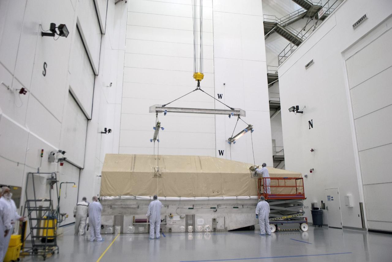 CAPE CANAVERAL, Fla. – Engineers lift the top off a shipping container for NASA's TDRS-L satellite inside the Astrotech payload processing facility in Titusville for launch processing. The TDRS is the latest spacecraft destined for the agency's constellation of communications satellites that allows nearly continuous contact with orbiting spacecraft ranging from the International Space Station and Hubble Space Telescope to the array of scientific observatories. Photo credit: NASA/Tim Jacobs