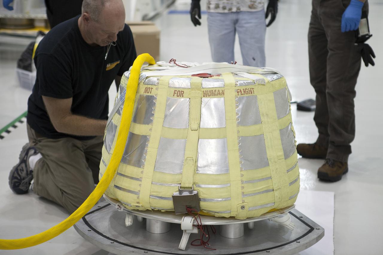 CAPE CANAVERAL, Fla. -- Inside the Operations and Checkout Building high bay at NASA’s Kennedy Space Center in Florida, technicians check the coverings on the main parachute for the Orion spacecraft. The parachute will be prepared for installation on Orion.     The Orion spacecraft is being prepared for its first unpiloted flight test, Exploration Flight Test-1, or EFT-1, scheduled for launch atop a Delta IV rocket in September 2014. The Orion spacecraft is designed to carry astronauts to destinations not yet explored by humans. It will have emergency abort capability, sustain the crew during space travel and provide safe re-entry from deep space return velocities. Orion is scheduled to launch atop NASA’s Space Launch System rocket in 2017. For more information, visit http://www.nasa.gov/orion. Photo credit: NASA/Kim Shiflett