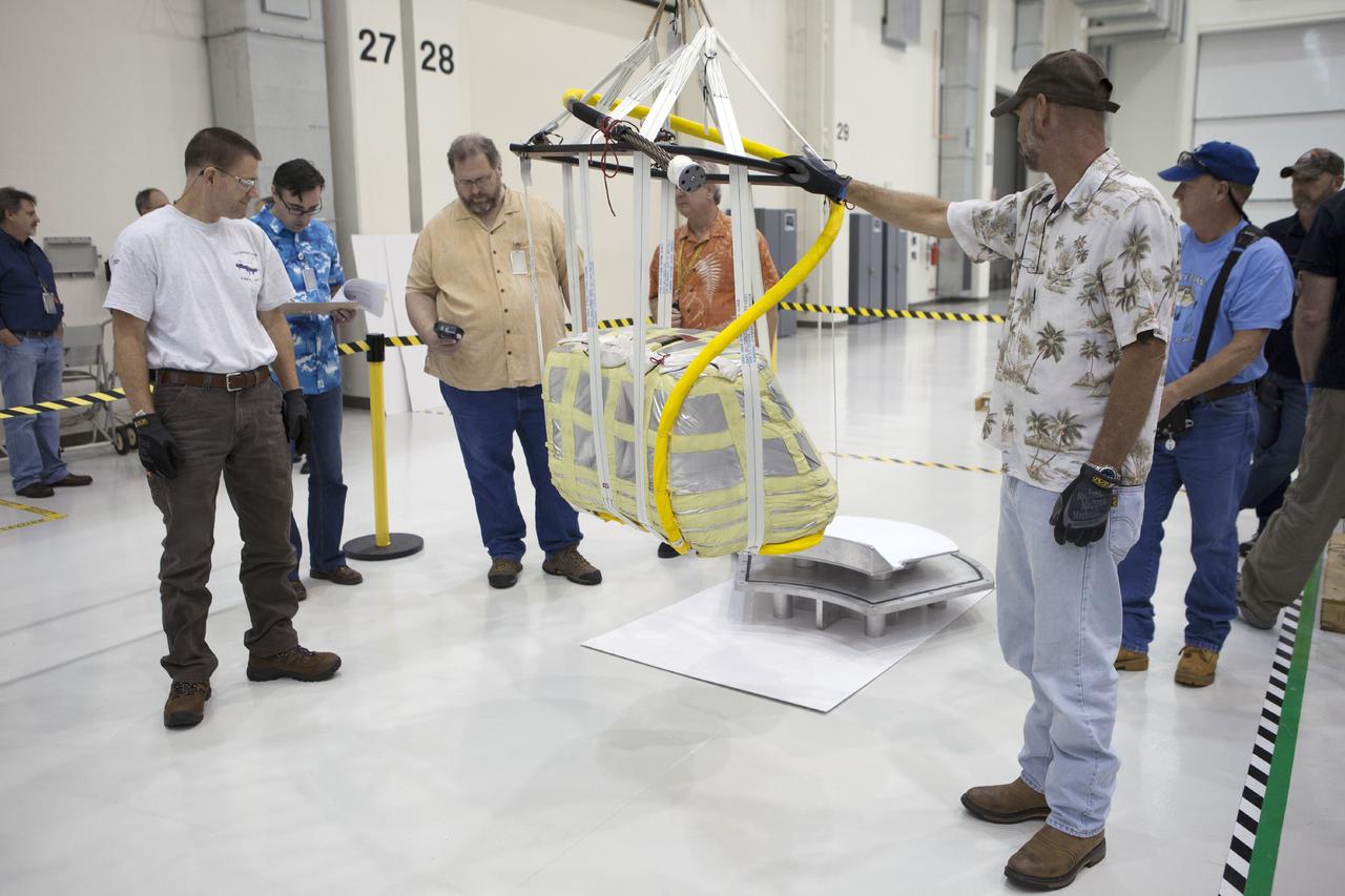 CAPE CANAVERAL, Fla. -- Technicians assist as a crane begins to lift one of the main parachutes for the Orion spacecraft inside the Operations and Checkout Building high bay at NASA’s Kennedy Space Center in Florida. The parachute will be prepared for installation on Orion.     The Orion spacecraft is being prepared for its first unpiloted flight test, Exploration Flight Test-1, or EFT-1, scheduled for launch atop a Delta IV rocket in September 2014. The Orion spacecraft is designed to carry astronauts to destinations not yet explored by humans. It will have emergency abort capability, sustain the crew during space travel and provide safe re-entry from deep space return velocities. Orion is scheduled to launch atop NASA’s Space Launch System rocket in 2017. For more information, visit http://www.nasa.gov/orion. Photo credit: NASA/Kim Shiflett