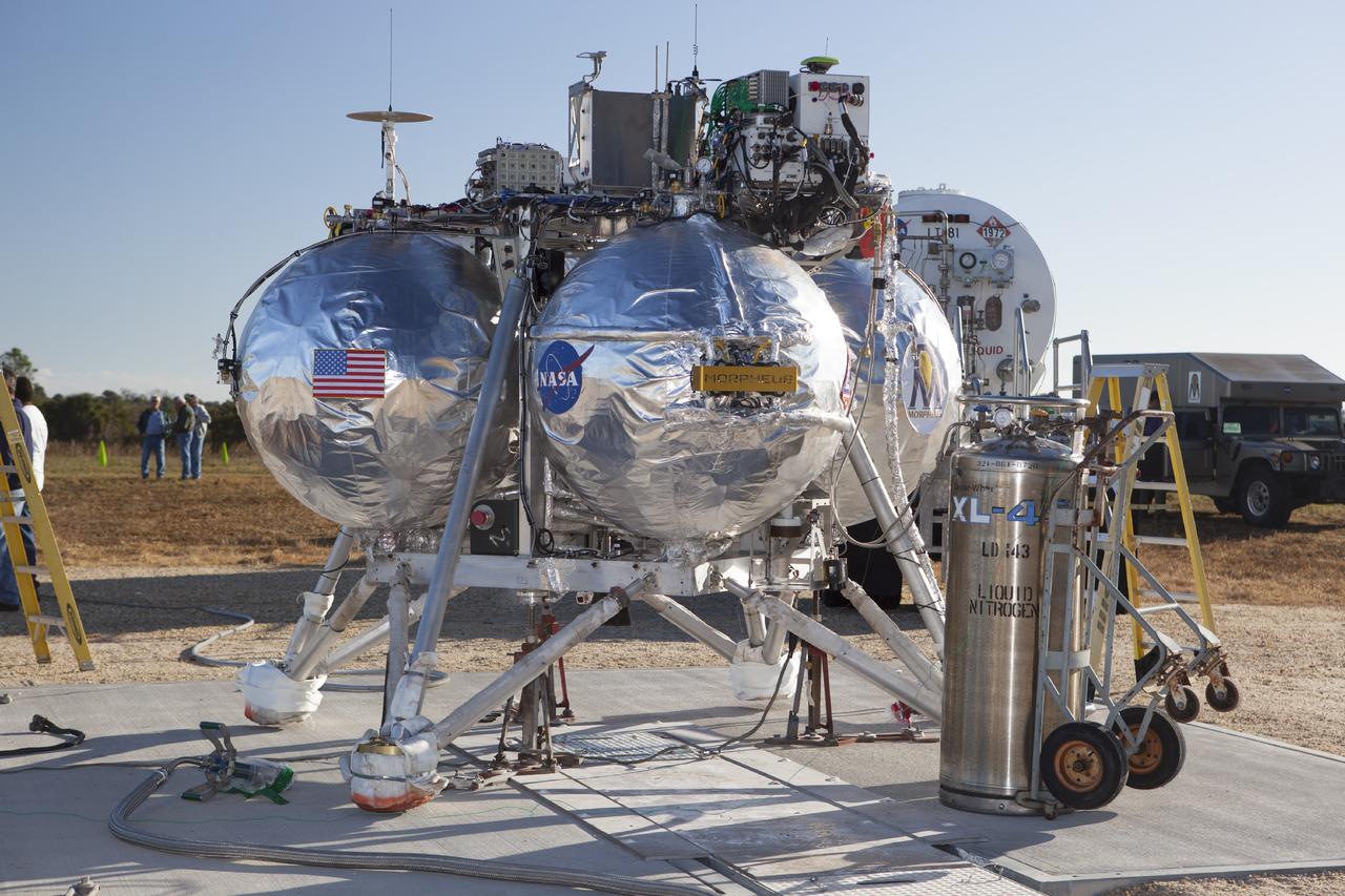 CAPE CANAVERAL, Fla. -- Preparations are underway to prepare the Project Morpheus prototype lander for a second free flight test at the north end of the Shuttle Landing Facility at NASA’s Kennedy Space Center in Florida. Testing of the prototype lander was performed at NASA’s Johnson Space Center in Houston in preparation for tethered and free flight testing at Kennedy. Project Morpheus integrates NASA’s automated landing and hazard avoidance technology, or ALHAT, with an engine that runs on liquid oxygen and methane, or green propellants, into a fully-operational lander that could deliver cargo to other planetary surfaces.    The landing facility will provide the lander with the kind of field necessary for realistic testing, complete with rocks, craters and hazards to avoid. Morpheus’ ALHAT payload allows it to navigate to clear landing sites amidst rocks, craters and other hazards during its descent. Project Morpheus is being managed under the Advanced Exploration Systems, or AES, Division in NASA’s Human Exploration and Operations Mission Directorate. The efforts in AES pioneer new approaches for rapidly developing prototype systems, demonstrating key capabilities and validating operational concepts for future human missions beyond Earth orbit. For more information on Project Morpheus, visit http://morpheuslander.jsc.nasa.gov.  Photo credit: NASA/Dimitri Gerondidakis