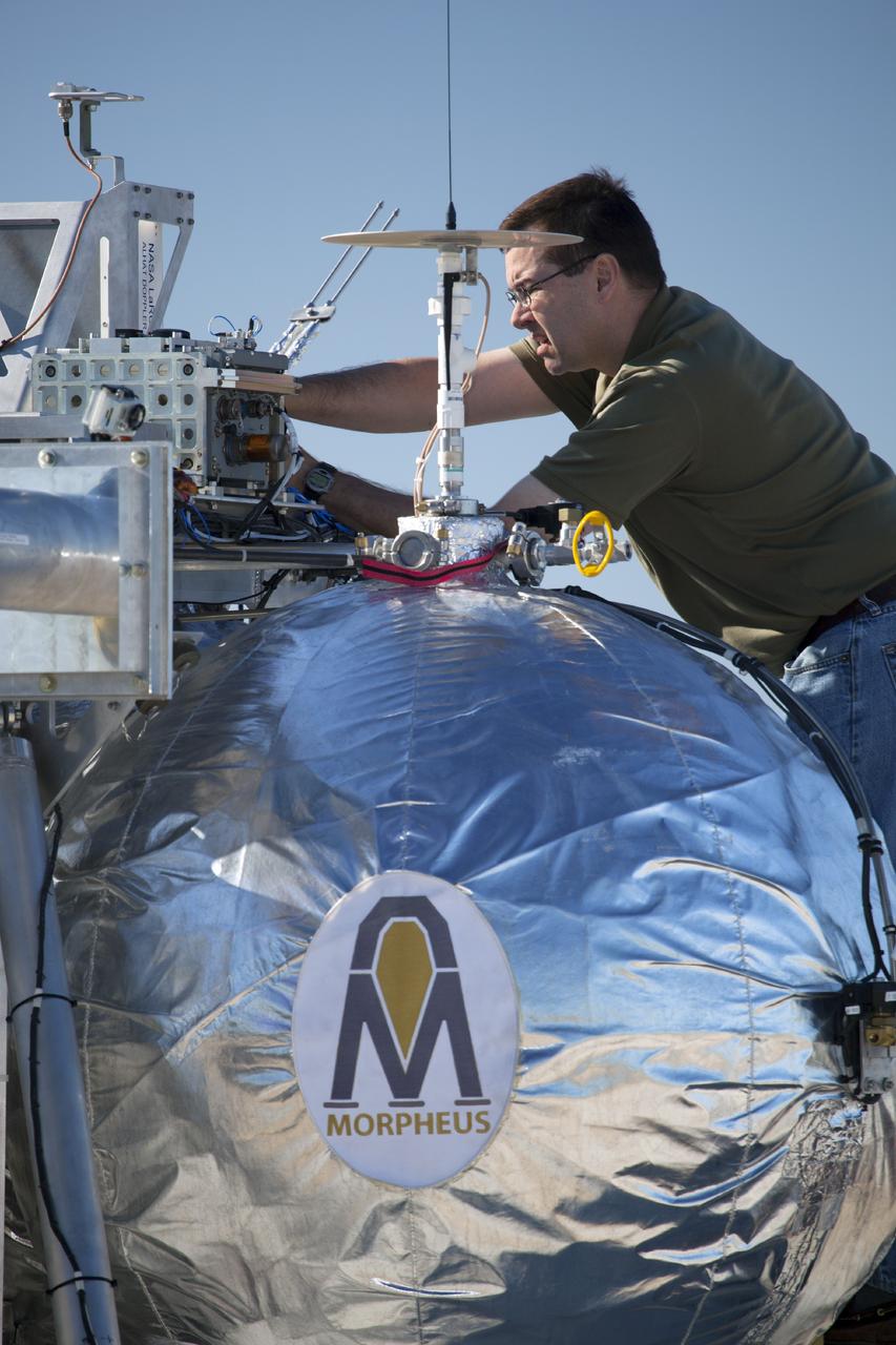 CAPE CANAVERAL, Fla. -- A technician prepares the Project Morpheus prototype lander for a second free flight test at the north end of the Shuttle Landing Facility at NASA’s Kennedy Space Center in Florida. Testing of the prototype lander was performed at NASA’s Johnson Space Center in Houston in preparation for tethered and free flight testing at Kennedy. Project Morpheus integrates NASA’s automated landing and hazard avoidance technology, or ALHAT, with an engine that runs on liquid oxygen and methane, or green propellants, into a fully-operational lander that could deliver cargo to other planetary surfaces.    The landing facility will provide the lander with the kind of field necessary for realistic testing, complete with rocks, craters and hazards to avoid. Morpheus’ ALHAT payload allows it to navigate to clear landing sites amidst rocks, craters and other hazards during its descent. Project Morpheus is being managed under the Advanced Exploration Systems, or AES, Division in NASA’s Human Exploration and Operations Mission Directorate. The efforts in AES pioneer new approaches for rapidly developing prototype systems, demonstrating key capabilities and validating operational concepts for future human missions beyond Earth orbit. For more information on Project Morpheus, visit http://morpheuslander.jsc.nasa.gov.  Photo credit: NASA/Dimitri Gerondidakis