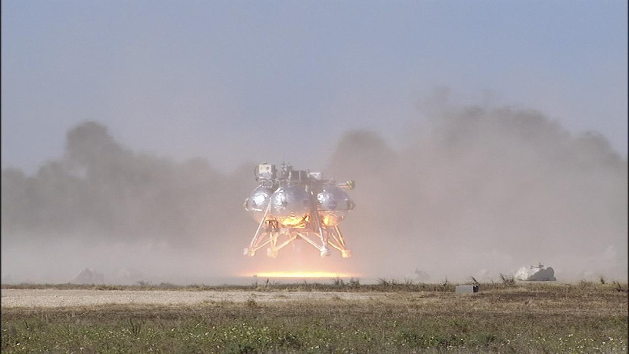 CAPE CANAVERAL, Fla. -- The second free flight of the Project Morpheus prototype lander was conducted at the north end of the Shuttle Landing Facility at NASA’s Kennedy Space Center in Florida. The 81-second test began at 1:37 p.m. EST with the Morpheus lander launching from the ground over a flame trench and ascending about 164 feet, pausing briefly at 82 feet. The lander flew forward, covering about 154 feet in 30 seconds before descending and landing on a dedicated landing pad inside the autonomous landing and hazard avoidance technology, or ALHAT, hazard field. Project Morpheus tests NASA’s ALHAT and an engine that runs on liquid oxygen and methane, or green propellants, into a fully-operational lander that could deliver cargo to other planetary surfaces.     The landing facility provides the lander with the kind of field necessary for realistic testing, complete with rocks, craters and hazards to avoid. Morpheus’ ALHAT payload allows it to navigate to clear landing sites amidst rocks, craters and other hazards during its descent. Project Morpheus is being managed under the Advanced Exploration Systems, or AES, Division in NASA’s Human Exploration and Operations Mission Directorate. The efforts in AES pioneer new approaches for rapidly developing prototype systems, demonstrating key capabilities and validating operational concepts for future human missions beyond Earth orbit. For more information on Project Morpheus, visit http://www.nasa.gov/centers/johnson/exploration/morpheus.  Photo credit: NASA/Chris Chamberland