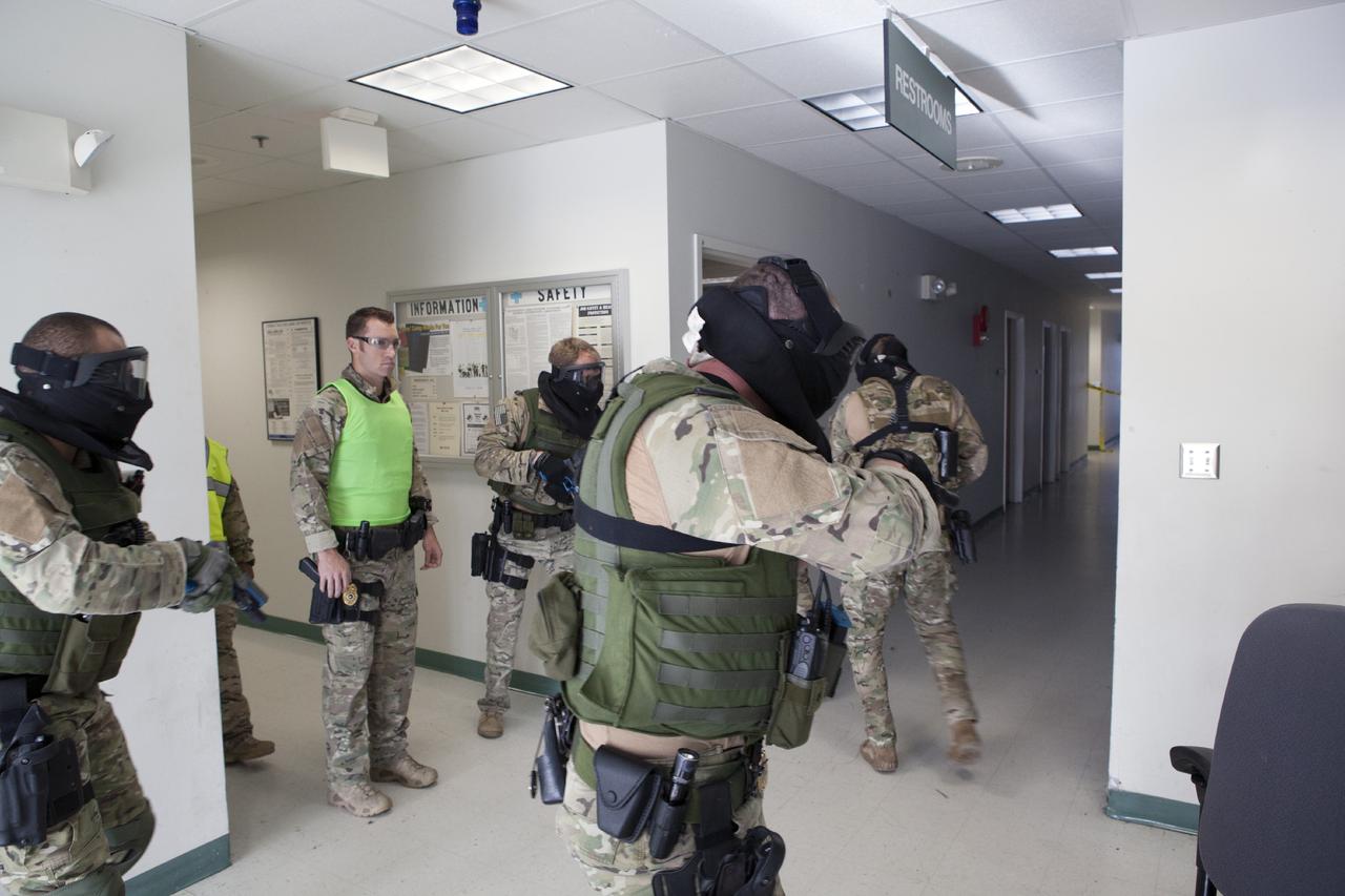 CAPE CANAVERAL, Fla. – At a training location near Launch Complex 39 at NASA’s Kennedy Space Center in Florida, members of the Emergency Response Team, or ERT, participate in specialized training simulations in order to keep their skills current. They are wearing full protective gear and carrying non-lethal firearms, which are denoted in blue, for the training exercises. The ERT training supervisor, wearing a bright green vest, monitors the training exercise and reviews procedures.    Recently, eight members of the ERT competed in the 31st Annual SWAT Roundup International competition in Orlando, Fla., and received recognition by placing in the top five overall.  In keeping with NASA’s commitment to safety and security of workforce and assets, the ERT is part of Kennedy’s security team and is trained to respond in the event of an emergency at the center.  Photo credit: NASA/Daniel Casper