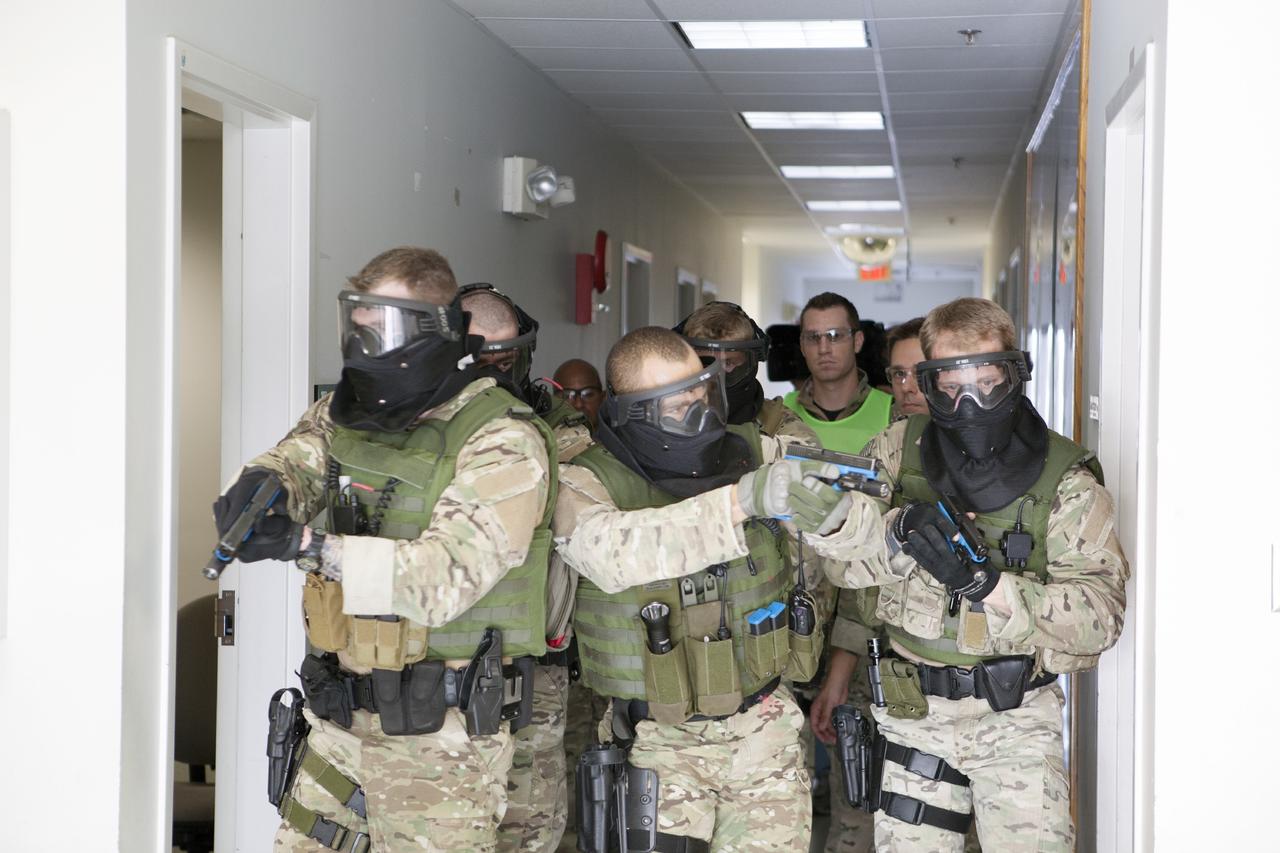 CAPE CANAVERAL, Fla. – At a training location near Launch Complex 39 at NASA’s Kennedy Space Center in Florida, members of the Emergency Response Team, or ERT, participate in specialized training simulations in order to keep their skills current. They are wearing full protective gear and carrying non-lethal firearms, which are denoted in blue, for the training exercises. In the background, the ERT training supervisor, wearing a bright green vest, monitors the training exercise and reviews procedures.    Recently, eight members of the ERT competed in the 31st Annual SWAT Roundup International competition in Orlando, Fla., and received recognition by placing in the top five overall.  In keeping with NASA’s commitment to safety and security of workforce and assets, the ERT is part of Kennedy’s security team and is trained to respond in the event of an emergency at the center.  Photo credit: NASA/Daniel Casper