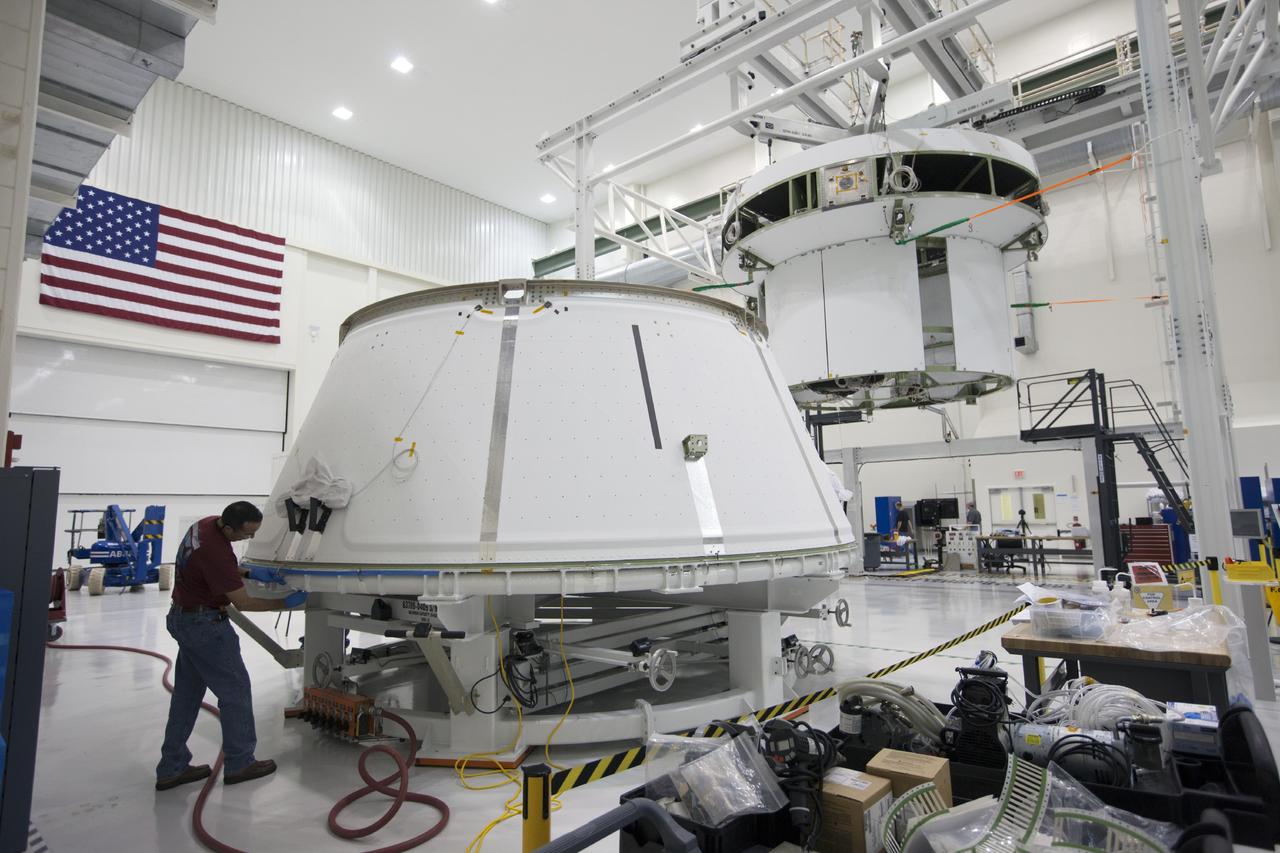 CAPE CANAVERAL, Fla. – Inside the Operations and Checkout Building at NASA’s Kennedy Space Center in Florida, the spacecraft adapter cone for the Orion vehicle is being prepared to be mated to the service module. In the background, the service module for Orion is suspended above the floor by a movable crane. Orion is the exploration spacecraft designed to carry astronauts to destinations not yet explored by humans, including an asteroid and Mars. It will have emergency abort capability, sustain the crew during space travel and provide safe re-entry from deep space return velocities. The first unpiloted test flight of the Orion is scheduled to launch in 2014 atop a Delta IV rocket and in 2017 on NASA’s Space Launch System rocket. For more information, visit http://www.nasa.gov/orion. Photo credit: NASA/Kim Shiflett