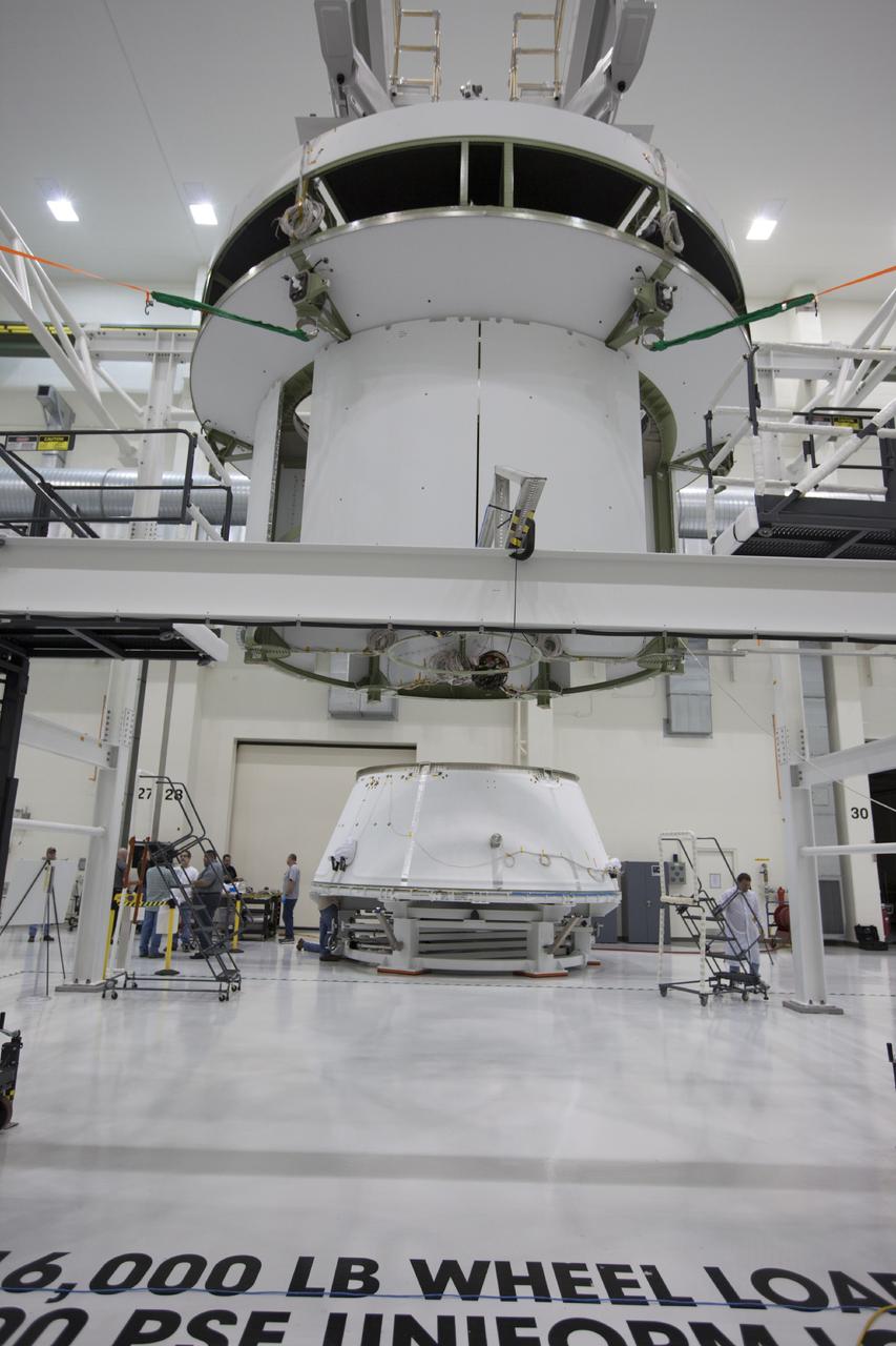 CAPE CANAVERAL, Fla. – Inside the Operations and Checkout Building at NASA’s Kennedy Space Center in Florida, workers position access stands near the service module for Orion, which is suspended above the floor by a movable crane. The spacecraft adapter cone for Orion is positioned on a stand and is being prepared for mating to the service module. Orion is the exploration spacecraft designed to carry astronauts to destinations not yet explored by humans, including an asteroid and Mars. It will have emergency abort capability, sustain the crew during space travel and provide safe re-entry from deep space return velocities. The first unpiloted test flight of the Orion is scheduled to launch in 2014 atop a Delta IV rocket and in 2017 on NASA’s Space Launch System rocket. For more information, visit http://www.nasa.gov/orion. Photo credit: NASA/Kim Shiflett