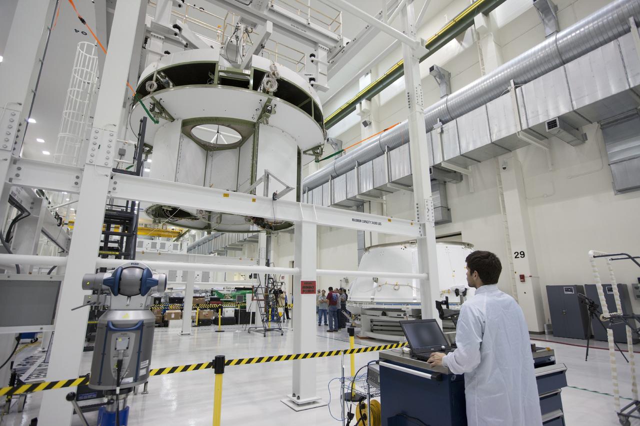 CAPE CANAVERAL, Fla. – Inside the Operations and Checkout Building at NASA’s Kennedy Space Center in Florida, technicians monitor the progress as a crane moves the service module for Orion in the high bay. To the right, the spacecraft adapter cone is secured on a work stand. Orion is the exploration spacecraft designed to carry astronauts to destinations not yet explored by humans, including an asteroid and Mars. It will have emergency abort capability, sustain the crew during space travel and provide safe re-entry from deep space return velocities. The first unpiloted test flight of the Orion is scheduled to launch in 2014 atop a Delta IV rocket and in 2017 on NASA’s Space Launch System rocket. For more information, visit http://www.nasa.gov/orion. Photo credit: NASA/Kim Shiflett
