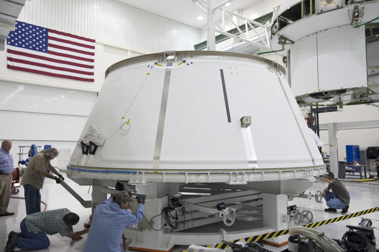 CAPE CANAVERAL, Fla. – Inside the Operations and Checkout Building at NASA’s Kennedy Space Center in Florida, the spacecraft adapter cone for the Orion vehicle is being prepared to be mated to the service module. In the background, the service module is suspended above the floor by a movable crane. Orion is the exploration spacecraft designed to carry astronauts to destinations not yet explored by humans, including an asteroid and Mars. It will have emergency abort capability, sustain the crew during space travel and provide safe re-entry from deep space return velocities. The first unpiloted test flight of the Orion is scheduled to launch in 2014 atop a Delta IV rocket and in 2017 on NASA’s Space Launch System rocket. For more information, visit http://www.nasa.gov/orion. Photo credit: NASA/Kim Shiflett