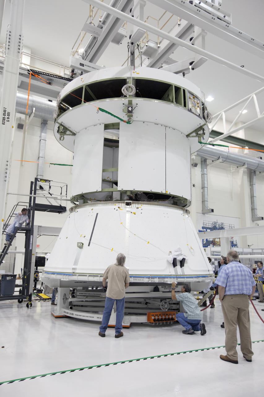 CAPE CANAVERAL, Fla. – Inside the Operations and Checkout Building at NASA’s Kennedy Space Center in Florida, workers position the spacecraft adapter cone for Orion underneath the service module, which is suspended above the floor by a movable crane. The service module will be attached to the adapter cone. Orion is the exploration spacecraft designed to carry astronauts to destinations not yet explored by humans, including an asteroid and Mars. It will have emergency abort capability, sustain the crew during space travel and provide safe re-entry from deep space return velocities. The first unpiloted test flight of the Orion is scheduled to launch in 2014 atop a Delta IV rocket and in 2017 on NASA’s Space Launch System rocket. For more information, visit http://www.nasa.gov/orion. Photo credit: NASA/Kim Shiflett