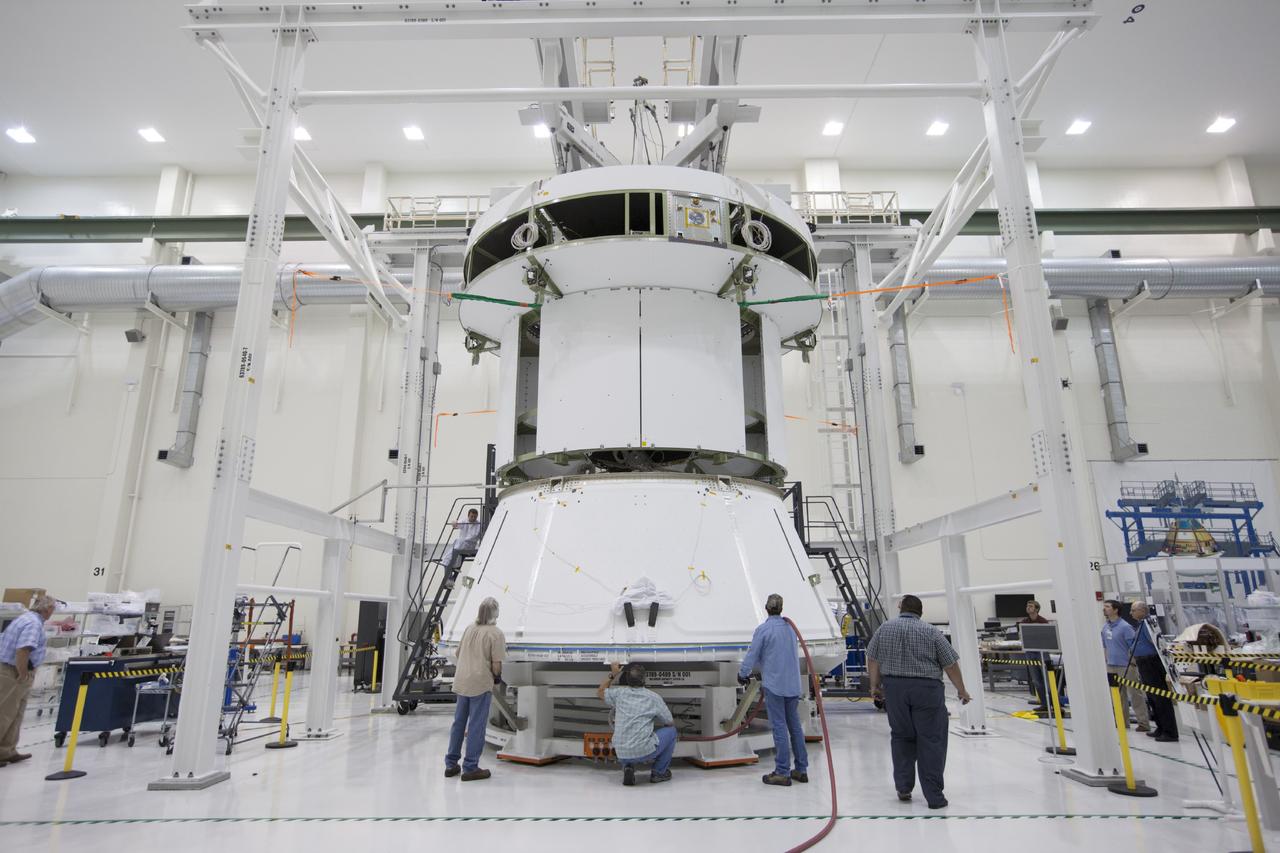 CAPE CANAVERAL, Fla. – Inside the Operations and Checkout Building at NASA’s Kennedy Space Center in Florida, workers position the spacecraft adapter cone for Orion underneath the service module, which is suspended above the floor by a movable crane. The service module will be attached to the adapter cone. Orion is the exploration spacecraft designed to carry astronauts to destinations not yet explored by humans, including an asteroid and Mars. It will have emergency abort capability, sustain the crew during space travel and provide safe re-entry from deep space return velocities. The first unpiloted test flight of the Orion is scheduled to launch in 2014 atop a Delta IV rocket and in 2017 on NASA’s Space Launch System rocket. For more information, visit http://www.nasa.gov/orion. Photo credit: NASA/Kim Shiflett