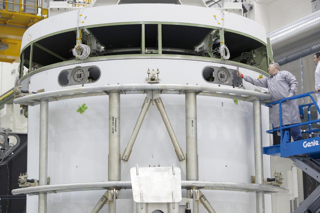 CAPE CANAVERAL, Fla. – Inside the Operations and Checkout Building high bay at NASA’s Kennedy Space Center in Florida, technicians on a scissor lift work on the installation of the second of three fairings on the service module for the Orion spacecraft.      The Orion spacecraft is being prepared for its first unpiloted flight test, Exploration Flight Test-1, or EFT-1, scheduled for launch atop a Delta IV rocket in September 2014. The Orion spacecraft is designed to carry astronauts to destinations not yet explored by humans. It will have emergency abort capability, sustain the crew during space travel and provide safe re-entry from deep space return velocities. Orion is scheduled to launch atop NASA’s Space Launch System rocket in 2017. For more information, visit http://www.nasa.gov/orion. Photo credit: NASA/Dimitri Gerondidakis