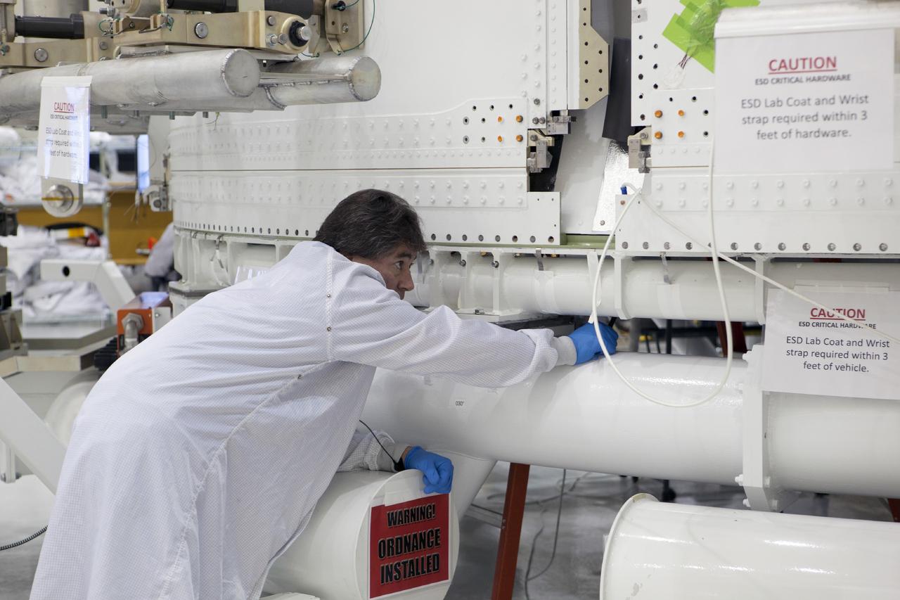 CAPE CANAVERAL, Fla. – Inside the Operations and Checkout Building high bay at NASA’s Kennedy Space Center in Florida, a technician closely monitors two fairings as they are joined together after being installed on the service module for the Orion spacecraft.      The Orion spacecraft is being prepared for its first unpiloted flight test, Exploration Flight Test-1, or EFT-1, scheduled for launch atop a Delta IV rocket in September 2014. The Orion spacecraft is designed to carry astronauts to destinations not yet explored by humans. It will have emergency abort capability, sustain the crew during space travel and provide safe re-entry from deep space return velocities. Orion is scheduled to launch atop NASA’s Space Launch System rocket in 2017. For more information, visit http://www.nasa.gov/orion. Photo credit: NASA/Dimitri Gerondidakis
