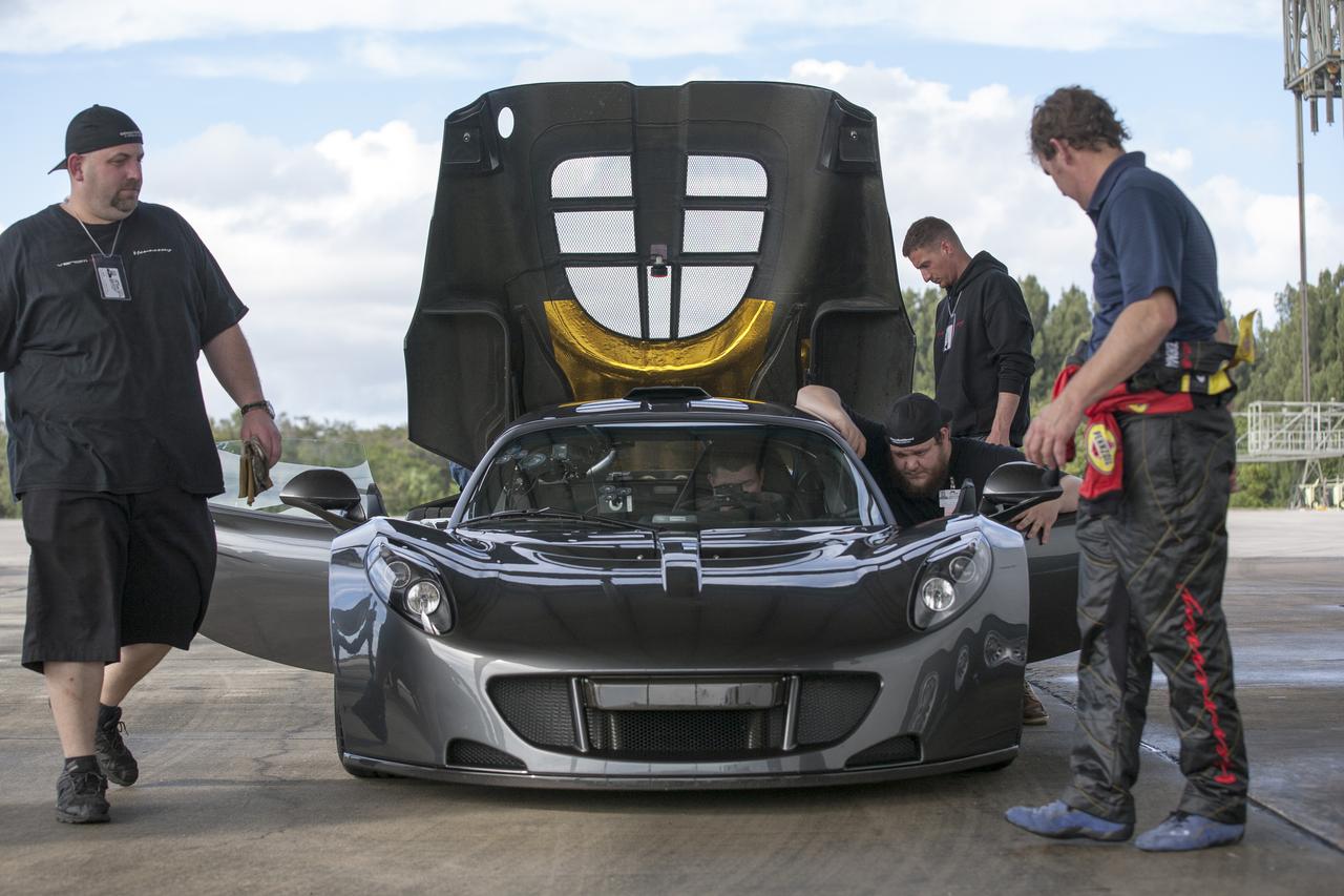 CAPE CANAVERAL, Fla. - Mechanics, engineers and Driver Brian Smith, in jumpsuit, ready a Hennessey Venom GT for test runs on the 3.5-mile long runway at the Shuttle Landing Facility at NASA's Kennedy Space Center in Florida. The flat concrete runway is one of the few places in the world where high performance automobiles can be tested for aerodynamic and safety designs. Hennessey Performance of Sealy, Texas, worked with Performance Power Racing in West Palm Beach to arrange use of the NASA facility. Performance Power Racing has conducted numerous engineering tests on the runway with a variety of vehicles. Photo credit: NASA/Kim Shiflett