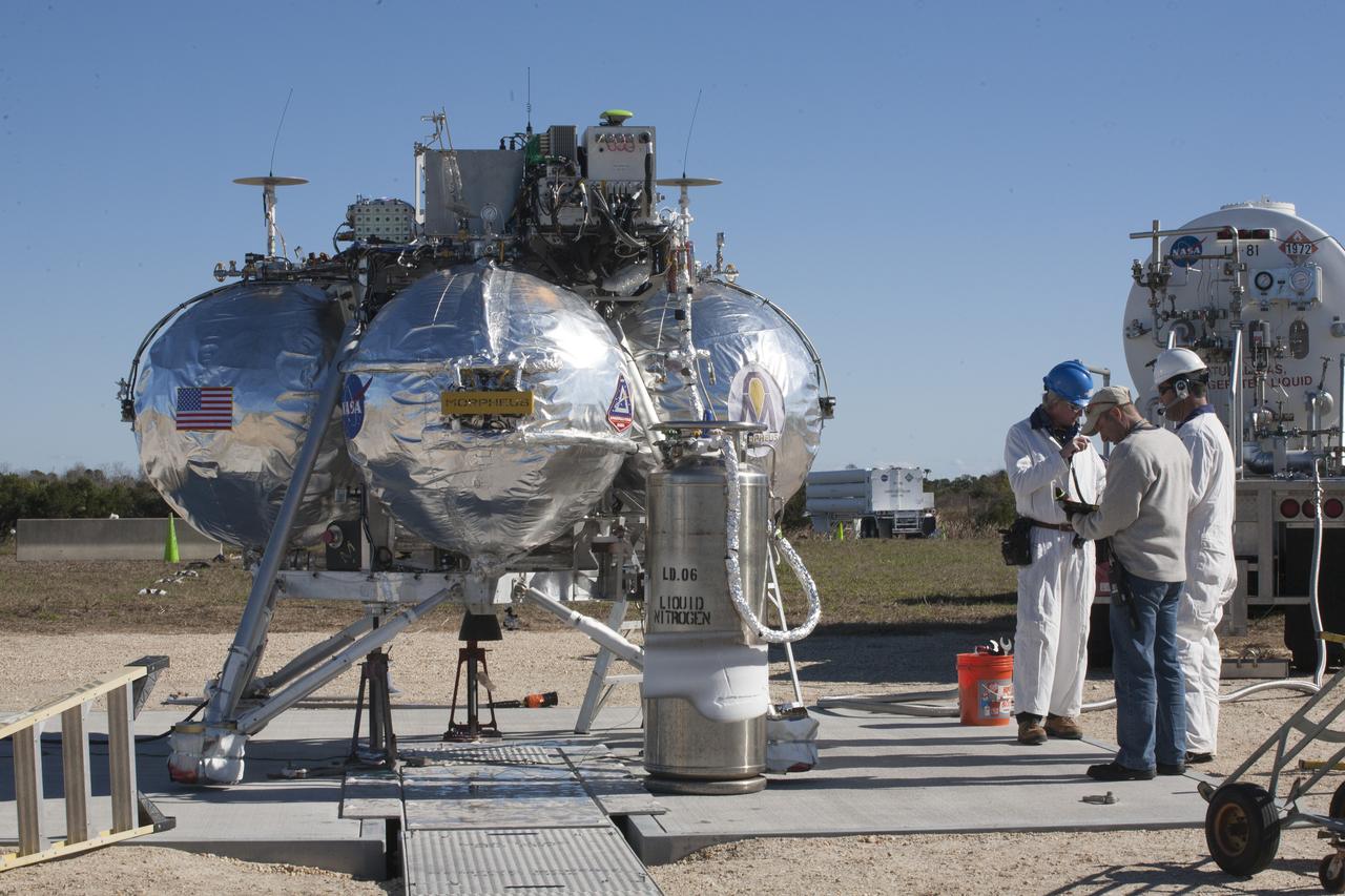 CAPE CANAVERAL, Fla. – The Project Morpheus prototype lander has been lowered onto the launch site and propellant is being loaded for its third free flight test at the north end of the Shuttle Landing Facility at NASA’s Kennedy Space Center in Florida. The 57-second test began at 1:15 p.m. EST with the Morpheus lander launching from the ground over a flame trench and ascending about 187 feet, nearly doubling the target ascent velocity from the last test in December 2013. The lander flew forward, covering about 154 feet in 20 seconds before descending and landing within 11 inches of its target on a dedicated pad inside the autonomous landing and hazard avoidance technology, or ALHAT, hazard field. Project Morpheus tests NASA’s ALHAT and an engine that runs on liquid oxygen and methane, or green propellants, into a fully-operational lander that could deliver cargo to other planetary surfaces. The landing facility provides the lander with the kind of field necessary for realistic testing, complete with rocks, craters and hazards to avoid. Morpheus’ ALHAT payload allows it to navigate to clear landing sites amidst rocks, craters and other hazards during its descent. Project Morpheus is being managed under the Advanced Exploration Systems, or AES, Division in NASA’s Human Exploration and Operations Mission Directorate. The efforts in AES pioneer new approaches for rapidly developing prototype systems, demonstrating key capabilities and validating operational concepts for future human missions beyond Earth orbit. For more information on Project Morpheus, visit http://www.nasa.gov/centers/johnson/exploration/morpheus. Photo credit: NASA/Kim Shiflett