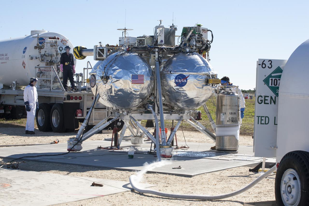 CAPE CANAVERAL, Fla. – Engineers and technicians monitor the progress as the Project Morpheus prototype lander is prepared for its third free flight test at the north end of the Shuttle Landing Facility at NASA’s Kennedy Space Center in Florida. The 57-second test began at 1:15 p.m. EST with the Morpheus lander launching from the ground over a flame trench and ascending about 187 feet, nearly doubling the target ascent velocity from the last test in December 2013. The lander flew forward, covering about 154 feet in 20 seconds before descending and landing within 11 inches of its target on a dedicated pad inside the autonomous landing and hazard avoidance technology, or ALHAT, hazard field. Project Morpheus tests NASA’s ALHAT and an engine that runs on liquid oxygen and methane, or green propellants, into a fully-operational lander that could deliver cargo to other planetary surfaces. The landing facility provides the lander with the kind of field necessary for realistic testing, complete with rocks, craters and hazards to avoid. Morpheus’ ALHAT payload allows it to navigate to clear landing sites amidst rocks, craters and other hazards during its descent. Project Morpheus is being managed under the Advanced Exploration Systems, or AES, Division in NASA’s Human Exploration and Operations Mission Directorate. The efforts in AES pioneer new approaches for rapidly developing prototype systems, demonstrating key capabilities and validating operational concepts for future human missions beyond Earth orbit. For more information on Project Morpheus, visit http://www.nasa.gov/centers/johnson/exploration/morpheus. Photo credit: NASA/Kim Shiflett  