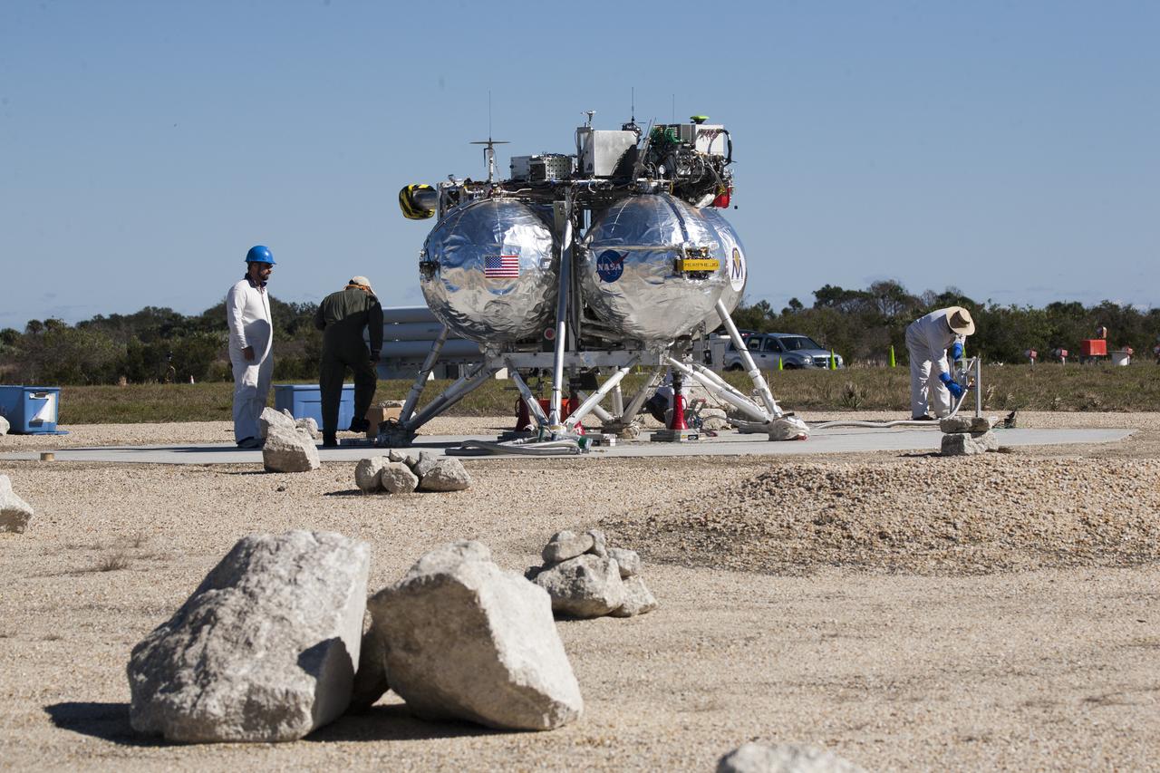 CAPE CANAVERAL, Fla. – The Project Morpheus prototype lander has been lowered onto the launch site for its third free flight test at the north end of the Shuttle Landing Facility at NASA’s Kennedy Space Center in Florida. The 57-second test began at 1:15 p.m. EST with the Morpheus lander launching from the ground over a flame trench and ascending about 187 feet, nearly doubling the target ascent velocity from the last test in December 2013. The lander flew forward, covering about 154 feet in 20 seconds before descending and landing within 11 inches of its target on a dedicated pad inside the autonomous landing and hazard avoidance technology, or ALHAT, hazard field. Project Morpheus tests NASA’s ALHAT and an engine that runs on liquid oxygen and methane, or green propellants, into a fully-operational lander that could deliver cargo to other planetary surfaces. The landing facility provides the lander with the kind of field necessary for realistic testing, complete with rocks, craters and hazards to avoid. Morpheus’ ALHAT payload allows it to navigate to clear landing sites amidst rocks, craters and other hazards during its descent. Project Morpheus is being managed under the Advanced Exploration Systems, or AES, Division in NASA’s Human Exploration and Operations Mission Directorate. The efforts in AES pioneer new approaches for rapidly developing prototype systems, demonstrating key capabilities and validating operational concepts for future human missions beyond Earth orbit. For more information on Project Morpheus, visit http://www.nasa.gov/centers/johnson/exploration/morpheus. Photo credit: NASA/Kim Shiflett  