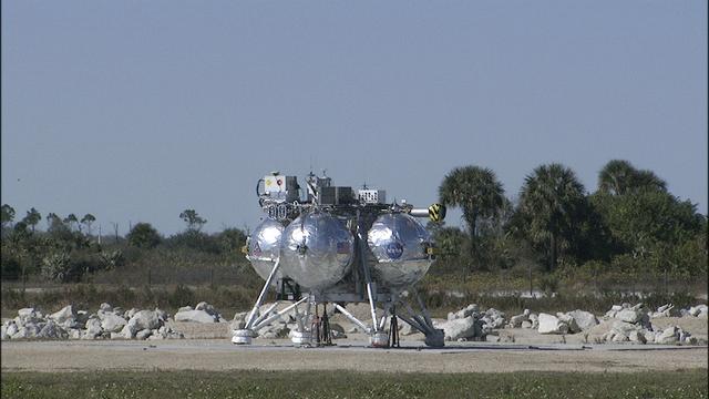 CAPE CANAVERAL, Fla. – The Project Morpheus prototype lander is positioned on a launch pad in preparation for its third free flight test at the north end of the Shuttle Landing Facility at NASA’s Kennedy Space Center in Florida. The 57-second test began at 1:15 p.m. EST with the Morpheus lander launching from the ground over a flame trench and ascending about 187 feet, nearly doubling the target ascent velocity from the last test in December 2013. The lander flew forward, covering about 154 feet in 20 seconds before descending and landing within 11 inches of its target on a dedicated pad inside the autonomous landing and hazard avoidance technology, or ALHAT, hazard field. Project Morpheus tests NASA’s ALHAT and an engine that runs on liquid oxygen and methane, or green propellants, into a fully-operational lander that could deliver cargo to other planetary surfaces. The landing facility provides the lander with the kind of field necessary for realistic testing, complete with rocks, craters and hazards to avoid. Morpheus’ ALHAT payload allows it to navigate to clear landing sites amidst rocks, craters and other hazards during its descent. Project Morpheus is being managed under the Advanced Exploration Systems, or AES, Division in NASA’s Human Exploration and Operations Mission Directorate. The efforts in AES pioneer new approaches for rapidly developing prototype systems, demonstrating key capabilities and validating operational concepts for future human missions beyond Earth orbit. For more information on Project Morpheus, visit http://www.nasa.gov/centers/johnson/exploration/morpheus. Photo credit: NASA/Frankie Martin