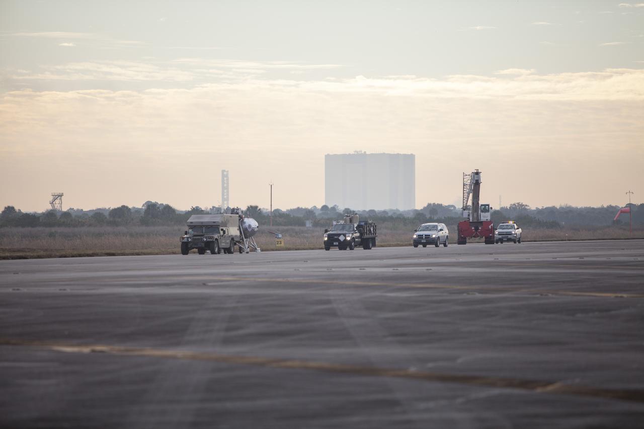 CAPE CANAVERAL, Fla. – The Project Morpheus prototype lander is transported to a launch pad at the north end of the Shuttle Landing Facility at NASA’s Kennedy Space Center in Florida. The prototype lander is being prepared for its fourth free flight test at Kennedy. Morpheus will launch from the ground over a flame trench and then descend and land on a dedicated pad inside the autonomous landing and hazard avoidance technology, or ALHAT, hazard field. Project Morpheus tests NASA’s ALHAT and an engine that runs on liquid oxygen and methane, or green propellants, into a fully-operational lander that could deliver cargo to other planetary surfaces. The landing facility provides the lander with the kind of field necessary for realistic testing, complete with rocks, craters and hazards to avoid. Morpheus’ ALHAT payload allows it to navigate to clear landing sites amidst rocks, craters and other hazards during its descent. Project Morpheus is being managed under the Advanced Exploration Systems, or AES, Division in NASA’s Human Exploration and Operations Mission Directorate. The efforts in AES pioneer new approaches for rapidly developing prototype systems, demonstrating key capabilities and validating operational concepts for future human missions beyond Earth orbit. For more information on Project Morpheus, visit http://www.nasa.gov/centers/johnson/exploration/morpheus. Photo credit: NASA/Cory Huston