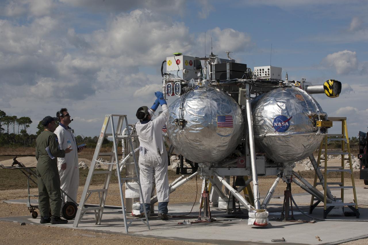 CAPE CANAVERAL, Fla. – The Project Morpheus prototype lander is positioned on a launch pad as engineers and technicians prepare it for the fourth free flight test at the north end of the Shuttle Landing Facility at NASA’s Kennedy Space Center in Florida. The 64-second test began at 1:15 p.m. EST with the Morpheus lander launching from the ground over a flame trench and ascending about 305 feet, significantly increasing the ascent velocity from the last test. The lander flew forward, covering about 358 feet in 25 seconds before descending and landing within 15 inches of its target on a dedicated pad inside the autonomous landing and hazard avoidance technology, or ALHAT, hazard field. Project Morpheus tests NASA’s ALHAT and an engine that runs on liquid oxygen and methane, or green propellants, into a fully-operational lander that could deliver cargo to other planetary surfaces. The landing facility provides the lander with the kind of field necessary for realistic testing, complete with rocks, craters and hazards to avoid. Morpheus’ ALHAT payload allows it to navigate to clear landing sites amidst rocks, craters and other hazards during its descent. Project Morpheus is being managed under the Advanced Exploration Systems, or AES, Division in NASA’s Human Exploration and Operations Mission Directorate. The efforts in AES pioneer new approaches for rapidly developing prototype systems, demonstrating key capabilities and validating operational concepts for future human missions beyond Earth orbit. For more information on Project Morpheus, visit http://www.nasa.gov/centers/johnson/exploration/morpheus. Photo credit: NASA/Kim Shiflett