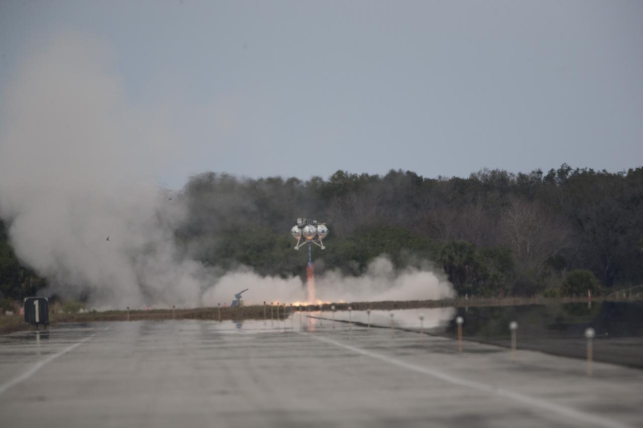CAPE CANAVERAL, Fla. – The Project Morpheus prototype lander begins to ascend after launching on its fourth free flight test at the north end of the Shuttle Landing Facility at NASA’s Kennedy Space Center in Florida. The 64-second test began at 1:15 p.m. EST with the Morpheus lander launching from the ground over a flame trench and ascending about 305 feet, significantly increasing the ascent velocity from the last test. The lander flew forward, covering about 358 feet in 25 seconds before descending and landing within 15 inches of its target on a dedicated pad inside the autonomous landing and hazard avoidance technology, or ALHAT, hazard field. Project Morpheus tests NASA’s ALHAT and an engine that runs on liquid oxygen and methane, or green propellants, into a fully-operational lander that could deliver cargo to other planetary surfaces. The landing facility provides the lander with the kind of field necessary for realistic testing, complete with rocks, craters and hazards to avoid. Morpheus’ ALHAT payload allows it to navigate to clear landing sites amidst rocks, craters and other hazards during its descent. Project Morpheus is being managed under the Advanced Exploration Systems, or AES, Division in NASA’s Human Exploration and Operations Mission Directorate. The efforts in AES pioneer new approaches for rapidly developing prototype systems, demonstrating key capabilities and validating operational concepts for future human missions beyond Earth orbit. For more information on Project Morpheus, visit http://www.nasa.gov/centers/johnson/exploration/morpheus. Photo credit: NASA/Kim Shiflett  