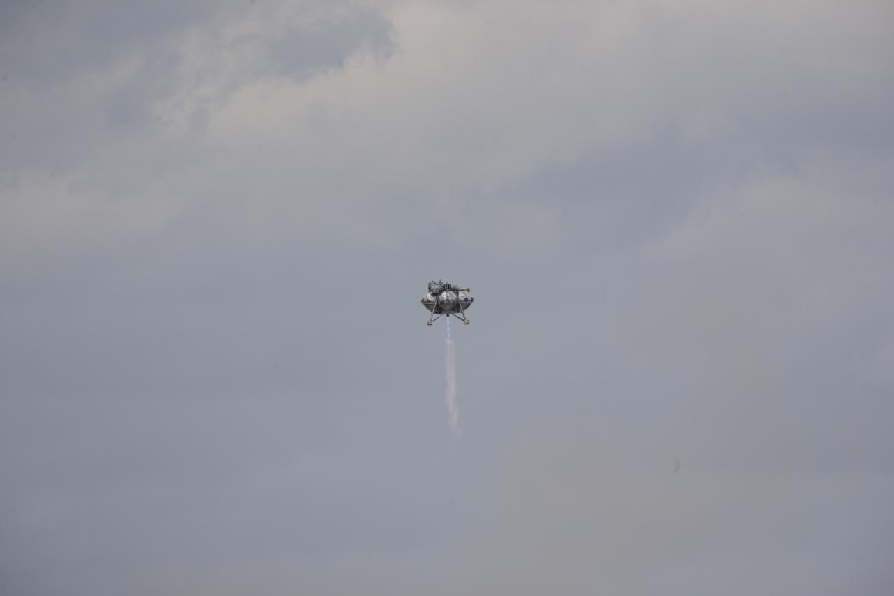 CAPE CANAVERAL, Fla. – The Project Morpheus prototype lander soars high after launching on its fourth free flight test at the north end of the Shuttle Landing Facility at NASA’s Kennedy Space Center in Florida. The 64-second test began at 1:15 p.m. EST with the Morpheus lander launching from the ground over a flame trench and ascending about 305 feet, significantly increasing the ascent velocity from the last test. The lander flew forward, covering about 358 feet in 25 seconds before descending and landing within 15 inches of its target on a dedicated pad inside the autonomous landing and hazard avoidance technology, or ALHAT, hazard field. Project Morpheus tests NASA’s ALHAT and an engine that runs on liquid oxygen and methane, or green propellants, into a fully-operational lander that could deliver cargo to other planetary surfaces. The landing facility provides the lander with the kind of field necessary for realistic testing, complete with rocks, craters and hazards to avoid. Morpheus’ ALHAT payload allows it to navigate to clear landing sites amidst rocks, craters and other hazards during its descent. Project Morpheus is being managed under the Advanced Exploration Systems, or AES, Division in NASA’s Human Exploration and Operations Mission Directorate. The efforts in AES pioneer new approaches for rapidly developing prototype systems, demonstrating key capabilities and validating operational concepts for future human missions beyond Earth orbit. For more information on Project Morpheus, visit http://www.nasa.gov/centers/johnson/exploration/morpheus. Photo credit: NASA/Kim Shiflett