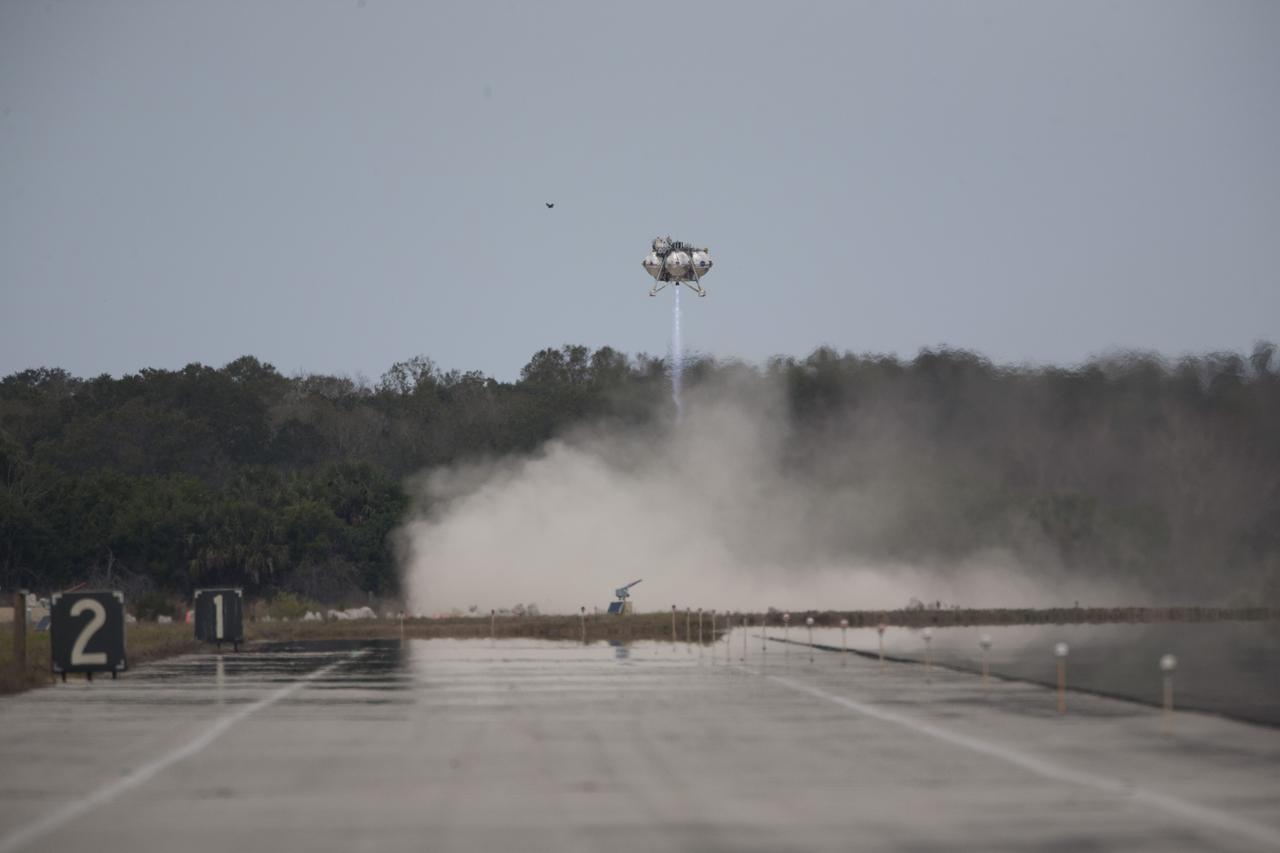 CAPE CANAVERAL, Fla. – The Project Morpheus prototype lander descends toward the autonomous landing and hazard avoidance technology, or ALHAT, hazard field after launching on its fourth free flight test at the north end of the Shuttle Landing Facility at NASA’s Kennedy Space Center in Florida. The 64-second test began at 1:15 p.m. EST with the Morpheus lander launching from the ground over a flame trench and ascending about 305 feet, significantly increasing the ascent velocity from the last test. The lander flew forward, covering about 358 feet in 25 seconds before descending and landing within 15 inches of its target on a dedicated pad inside the ALHAT hazard field. Project Morpheus tests NASA’s ALHAT and an engine that runs on liquid oxygen and methane, or green propellants, into a fully-operational lander that could deliver cargo to other planetary surfaces. The landing facility provides the lander with the kind of field necessary for realistic testing, complete with rocks, craters and hazards to avoid. Morpheus’ ALHAT payload allows it to navigate to clear landing sites amidst rocks, craters and other hazards during its descent. Project Morpheus is being managed under the Advanced Exploration Systems, or AES, Division in NASA’s Human Exploration and Operations Mission Directorate. The efforts in AES pioneer new approaches for rapidly developing prototype systems, demonstrating key capabilities and validating operational concepts for future human missions beyond Earth orbit. For more information on Project Morpheus, visit http://www.nasa.gov/centers/johnson/exploration/morpheus. Photo credit: NASA/Kim Shiflett  
