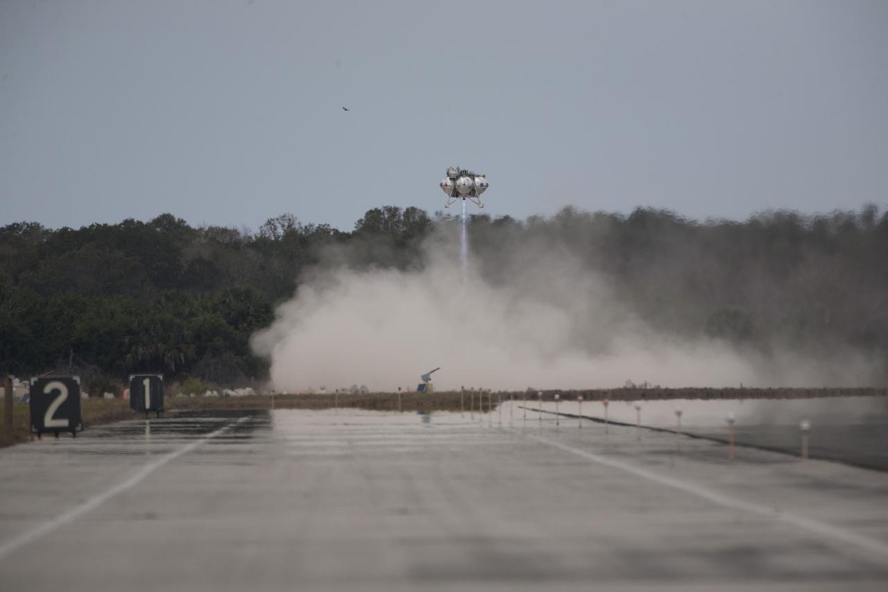 CAPE CANAVERAL, Fla. – The Project Morpheus prototype lander descends toward the autonomous landing and hazard avoidance technology, or ALHAT, hazard field after launching on its fourth free flight test at the north end of the Shuttle Landing Facility at NASA’s Kennedy Space Center in Florida. The 64-second test began at 1:15 p.m. EST with the Morpheus lander launching from the ground over a flame trench and ascending about 305 feet, significantly increasing the ascent velocity from the last test. The lander flew forward, covering about 358 feet in 25 seconds before descending and landing within 15 inches of its target on a dedicated pad inside the ALHAT hazard field. Project Morpheus tests NASA’s ALHAT and an engine that runs on liquid oxygen and methane, or green propellants, into a fully-operational lander that could deliver cargo to other planetary surfaces. The landing facility provides the lander with the kind of field necessary for realistic testing, complete with rocks, craters and hazards to avoid. Morpheus’ ALHAT payload allows it to navigate to clear landing sites amidst rocks, craters and other hazards during its descent. Project Morpheus is being managed under the Advanced Exploration Systems, or AES, Division in NASA’s Human Exploration and Operations Mission Directorate. The efforts in AES pioneer new approaches for rapidly developing prototype systems, demonstrating key capabilities and validating operational concepts for future human missions beyond Earth orbit. For more information on Project Morpheus, visit http://www.nasa.gov/centers/johnson/exploration/morpheus. Photo credit: NASA/Kim Shiflett