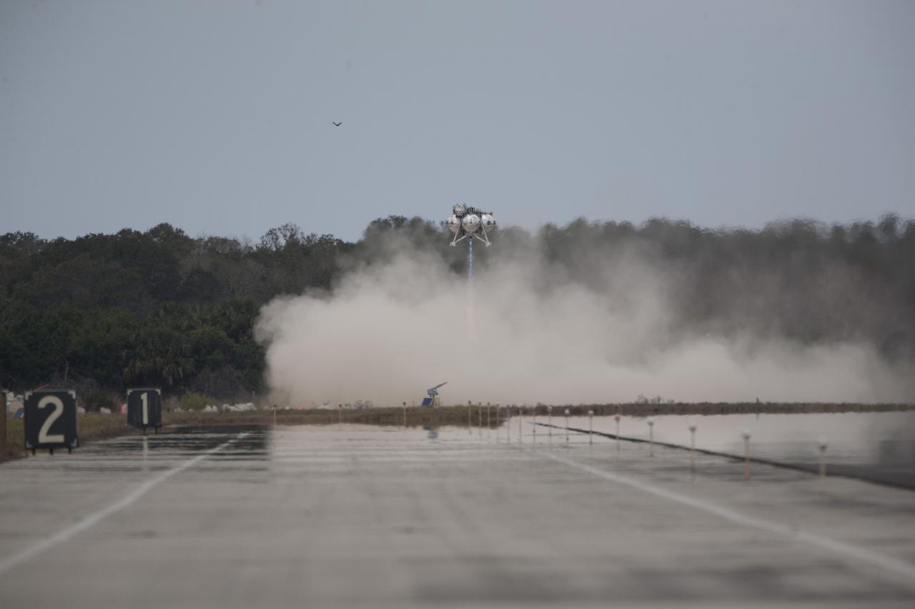 CAPE CANAVERAL, Fla. – The Project Morpheus prototype lander descends toward the autonomous landing and hazard avoidance technology, or ALHAT, hazard field after launching on its fourth free flight test at the north end of the Shuttle Landing Facility at NASA’s Kennedy Space Center in Florida. The 64-second test began at 1:15 p.m. EST with the Morpheus lander launching from the ground over a flame trench and ascending about 305 feet, significantly increasing the ascent velocity from the last test. The lander flew forward, covering about 358 feet in 25 seconds before descending and landing within 15 inches of its target on a dedicated pad inside the ALHAT hazard field. Project Morpheus tests NASA’s ALHAT and an engine that runs on liquid oxygen and methane, or green propellants, into a fully-operational lander that could deliver cargo to other planetary surfaces. The landing facility provides the lander with the kind of field necessary for realistic testing, complete with rocks, craters and hazards to avoid. Morpheus’ ALHAT payload allows it to navigate to clear landing sites amidst rocks, craters and other hazards during its descent. Project Morpheus is being managed under the Advanced Exploration Systems, or AES, Division in NASA’s Human Exploration and Operations Mission Directorate. The efforts in AES pioneer new approaches for rapidly developing prototype systems, demonstrating key capabilities and validating operational concepts for future human missions beyond Earth orbit. For more information on Project Morpheus, visit http://www.nasa.gov/centers/johnson/exploration/morpheus. Photo credit: NASA/Kim Shiflett