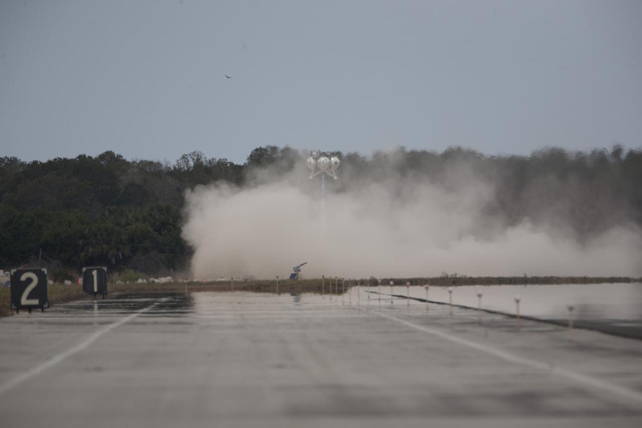 CAPE CANAVERAL, Fla. – The Project Morpheus prototype lander descends toward the autonomous landing and hazard avoidance technology, or ALHAT, hazard field after launching on its fourth free flight test at the north end of the Shuttle Landing Facility at NASA’s Kennedy Space Center in Florida. The 64-second test began at 1:15 p.m. EST with the Morpheus lander launching from the ground over a flame trench and ascending about 305 feet, significantly increasing the ascent velocity from the last test. The lander flew forward, covering about 358 feet in 25 seconds before descending and landing within 15 inches of its target on a dedicated pad inside the ALHAT hazard field. Project Morpheus tests NASA’s ALHAT and an engine that runs on liquid oxygen and methane, or green propellants, into a fully-operational lander that could deliver cargo to other planetary surfaces. The landing facility provides the lander with the kind of field necessary for realistic testing, complete with rocks, craters and hazards to avoid. Morpheus’ ALHAT payload allows it to navigate to clear landing sites amidst rocks, craters and other hazards during its descent. Project Morpheus is being managed under the Advanced Exploration Systems, or AES, Division in NASA’s Human Exploration and Operations Mission Directorate. The efforts in AES pioneer new approaches for rapidly developing prototype systems, demonstrating key capabilities and validating operational concepts for future human missions beyond Earth orbit. For more information on Project Morpheus, visit http://www.nasa.gov/centers/johnson/exploration/morpheus. Photo credit: NASA/Kim Shiflett