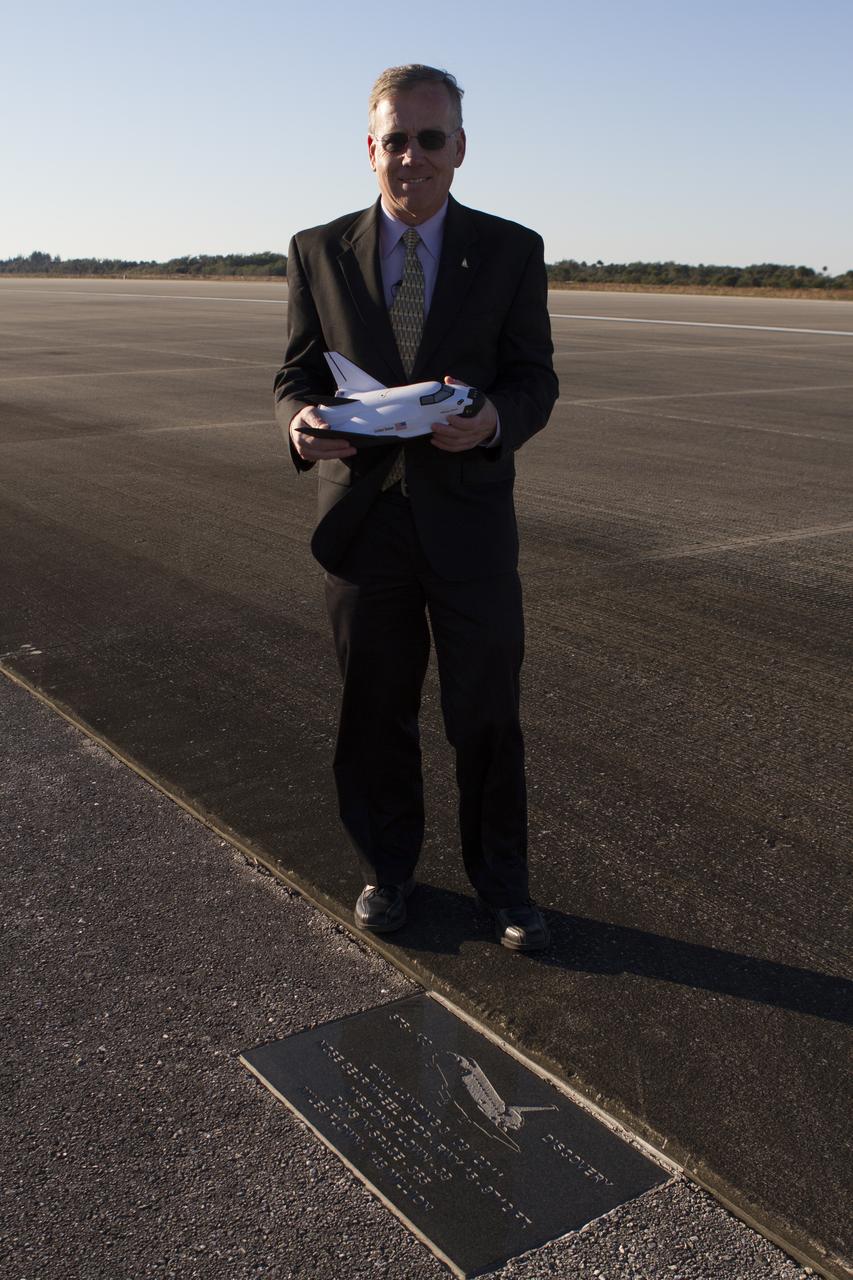 CAPE CANAVERAL, Fla. – Steve Lindsey, former NASA astronaut and Dream Chaser program manager for Sierra Nevada Corporation, or SNC, Space Systems stands at a plaque honoring the final landing of space shuttle Discovery on the 3.5-mile-long runway at Kennedy Space Center’s Shuttle Landing Facility. Lindsey, who was the commander of Discovery’s STS-133 mission, is holding a model of SNC’s Dream Chaser. SNC announced it plans to work with United Launch Alliance, or ULA, to launch the Dream Chaser spacecraft into orbit atop an Atlas V rocket from Space Launch Complex 41 at Cape Canaveral Air Force Station in November 2016 intends to land the winged spacecraft at the Shuttle Landing Facility lease office space at Exploration Park, right outside Kennedy’s gates and process the spacecraft in the high bay of the Operations and Checkout Building at Kennedy, with Lockheed Martin performing the work. The announcements made during a news conference at Kennedy are considered substantial for SNC and important to plans by NASA and Space Florida for Kennedy’s transformation into a multi-user spaceport for both commercial and government customers. Photo credit: NASA/Cory Huston  