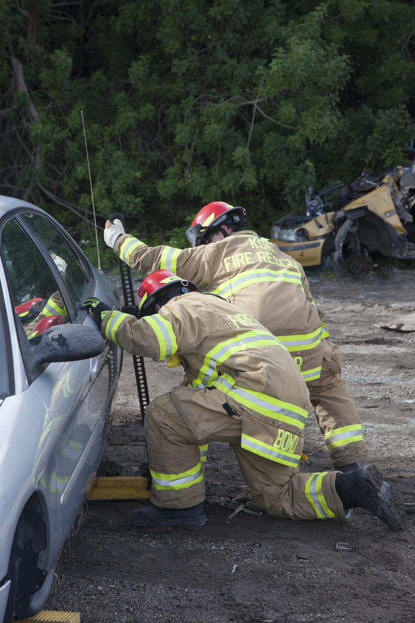 CAPE CANAVERAL, Fla. – Special Rescue Operations firefighters with NASA Fire Rescue Services in the Protective Services Office at NASA’s Kennedy Space Center in Florida practice vehicle extrication training at an auto salvage yard near the center. Two firefighters insert blocks under the vehicle to stabilize it. They will use the Jaws of Life on the vehicle to simulate the rescue of a trapped and injured person. Other rescue equipment includes axes, tools to punch through and clear away the windshield and windows and a hydraulic cutting tool that is used to remove the roof of a car.    Kennedy’s firefighters recently achieved Pro Board Certification in aerial fire truck operations. With the completion of vehicle extrication and Jaws of Life training, the Protective Services Office is one step closer to achieving certification in vehicle machinery extrication. Kennedy’s firefighters are with G4S Government Solutions Inc., on the Kennedy Protective Services Contract. Photo credit: NASA/Daniel Casper