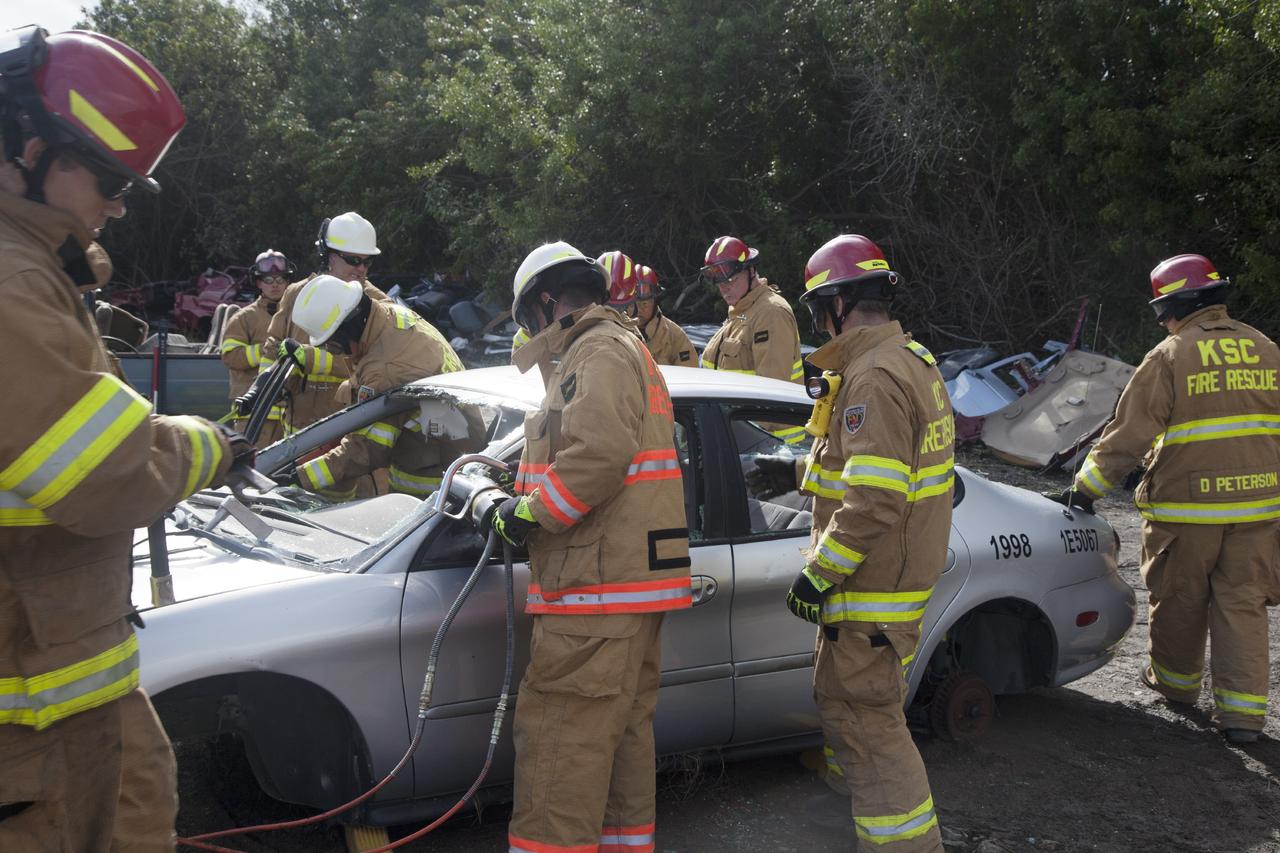 CAPE CANAVERAL, Fla. – Special Rescue Operations firefighters with NASA Fire Rescue Services in the Protective Services Office at NASA’s Kennedy Space Center in Florida practice vehicle extrication training at an auto salvage yard near the center. A firefighter uses a special hydraulic tool to cut through a section of the car to remove the roof, while other firefighters clear the windows and prepare to use the Jaws of Life to simulate the rescue of a trapped and injured person. Other rescue equipment being used includes axes and tools to punch through and clear away windshields and windows.     Kennedy’s firefighters recently achieved Pro Board Certification in aerial fire truck operations. With the completion of vehicle extrication and Jaws of Life training, the Protective Services Office is one step closer to achieving certification in vehicle machinery extrication. Kennedy’s firefighters are with G4S Government Solutions Inc., on the Kennedy Protective Services Contract. Photo credit: NASA/Daniel Casper