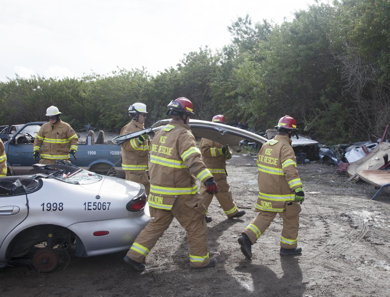 CAPE CANAVERAL, Fla. – Special Rescue Operations firefighters with NASA Fire Rescue Services in the Protective Services Office at NASA’s Kennedy Space Center in Florida practice vehicle extrication training at an auto salvage yard near the center. Firefighters carry away the roof of the car that was removed using a special hydraulic cutting tool and reciprocating saw. Other firefighters used axes and special tools to punch through and clear away the windshield and windows. They will use the Jaws of Life to simulate the rescue of a trapped and injured person.     Kennedy’s firefighters recently achieved Pro Board Certification in aerial fire truck operations. With the completion of vehicle extrication and Jaws of Life training, the Protective Services Office is one step closer to achieving certification in vehicle machinery extrication. Kennedy’s firefighters are with G4S Government Solutions Inc., on the Kennedy Protective Services Contract. Photo credit: NASA/Daniel Casper