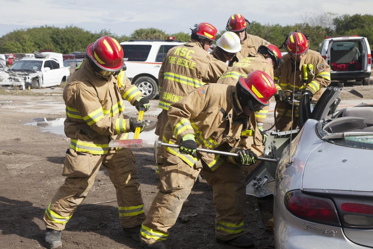 CAPE CANAVERAL, Fla. – Special Rescue Operations firefighters with NASA Fire Rescue Services in the Protective Services Office at NASA’s Kennedy Space Center in Florida practice vehicle extrication training at an auto salvage yard near the center. In the foreground, a firefighter with an axe assists as another firefighter uses a special tool to punch through the door of the vehicle. A special hydraulic cutting tool and reciprocating saw were used to cut through and remove the roof. In the background, other firefighters are practicing with the Jaws of Life to simulate the rescue of a trapped and injured person.      Kennedy’s firefighters recently achieved Pro Board Certification in aerial fire truck operations. With the completion of vehicle extrication and Jaws of Life training, the Protective Services Office is one step closer to achieving certification in vehicle machinery extrication. Kennedy’s firefighters are with G4S Government Solutions Inc., on the Kennedy Protective Services Contract. Photo credit: NASA/Daniel Casper