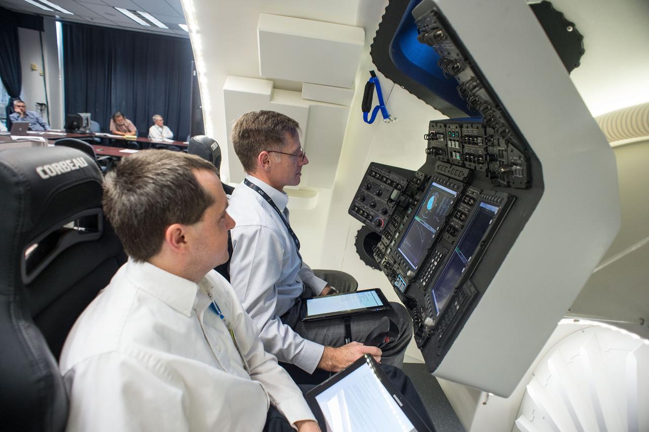 HOUSTON – Chris Ferguson, a former space shuttle commander who is now  director of Crew and Mission Operations for Boeing Space Exploration, takes the controls inside the company's CST-100 spacecraft simulator. To Ferguson's right, an engineer observes the exercise. Boeing demonstrated that the CST-100's software allows a human pilot to take over control of the spacecraft from the computer during all phases of a mission following separation from the launch vehicle. The pilot-in-the-loop demonstration at the Houston Product Support Center is a milestone under Boeing's Commercial Crew Integrated Capability agreement with the agency and its Commercial Crew Program. Photo credit: NASA/Bill Stafford