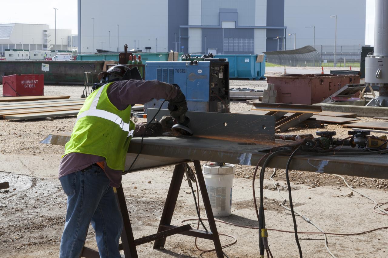 CAPE CANAVERAL, Fla. – Modifications continue on the Mobile Launcher, or ML, at the Mobile Launcher Park Site at NASA’s Kennedy Space Center in Florida. A construction worker prepares a metal beam that will be attached to the ML. In 2013, the agency awarded a contract to J.P. Donovan Construction Inc. of Rockledge, Fla., to modify the ML, which is one of the key elements of ground support equipment that is being upgraded by the Ground Systems Development and Operations Program office at Kennedy. The ML will carry the SLS rocket and Orion spacecraft to Launch Pad 39B for its first mission, Exploration Mission 1, in 2017. Photo credit: NASA/Dimitri Gerondidakis