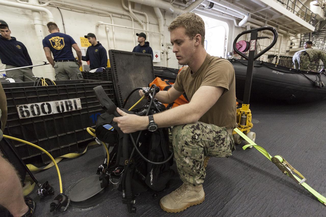 SAN DIEGO, Calif. – U.S. Navy personnel check support equipment aboard the USS San Diego at the U.S. Naval Base San Diego in California, in preparation for an Orion underway recovery test. The Orion boilerplate test vehicle was transported in the ship’s well deck about 100 miles offshore for an underway recovery test. NASA and the U.S. Navy conducted tests to prepare for recovery of the Orion crew module, forward bay cover and parachutes on its return from a deep space mission. The underway recovery test will allow the teams to demonstrate and evaluate the recovery processes, procedures, hardware and personnel in open waters. During the testing, the tether lines were unable to support the tension caused by crew module motion that was driven by wave turbulence in the well deck of the ship. NASA and the U.S. Navy are reviewing the testing data collected to evaluate the next steps. The Ground Systems Development and Operations Program conducted the underway recovery tests. Orion is the exploration spacecraft designed to carry astronauts to destinations not yet explored by humans, including an asteroid and Mars. It will have emergency abort capability, sustain the crew during space travel and provide safe re-entry from deep space return velocities. The first unpiloted test flight of the Orion is scheduled to launch in 2014 atop a Delta IV rocket and in 2017 on NASA’s Space Launch System rocket. For more information, visit http://www.nasa.gov/orion. Photo credit: NASA/Cory Huston